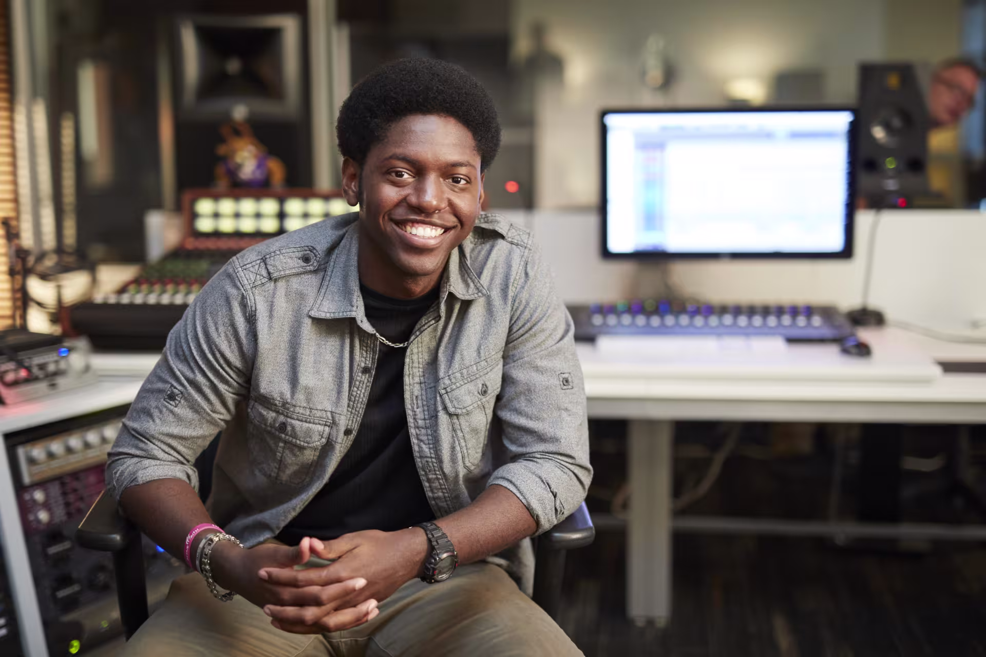 Male music production major smiling in front of computer in studio