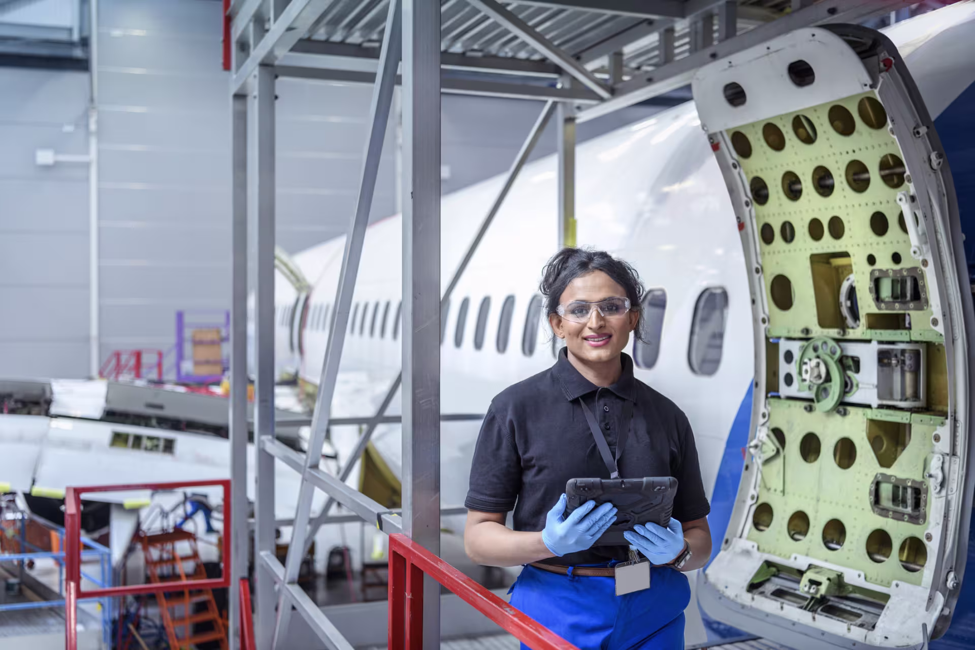 Aerospace engineer works on plane and smiles for camera