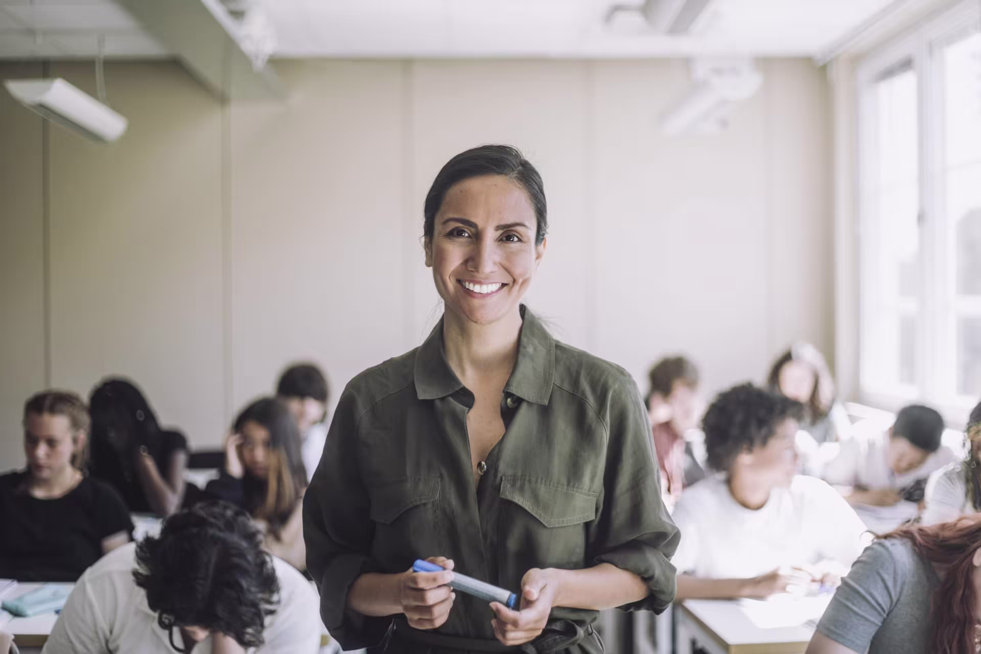 Secondary humanities teacher smiling in front of classroom