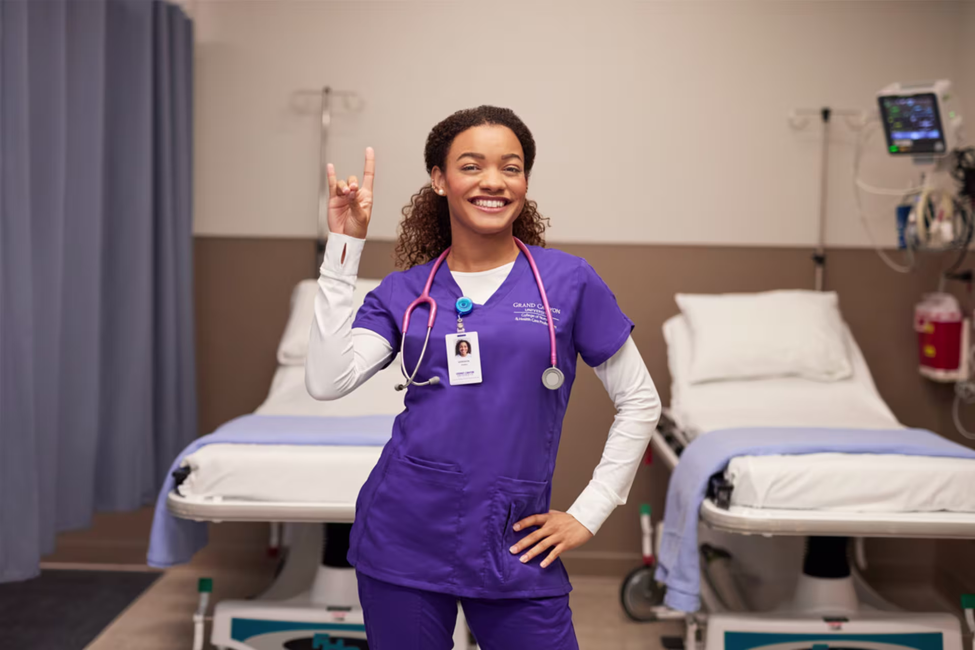 African-american female student in purple gcu absn scrubs gives lopes up sign with right hand