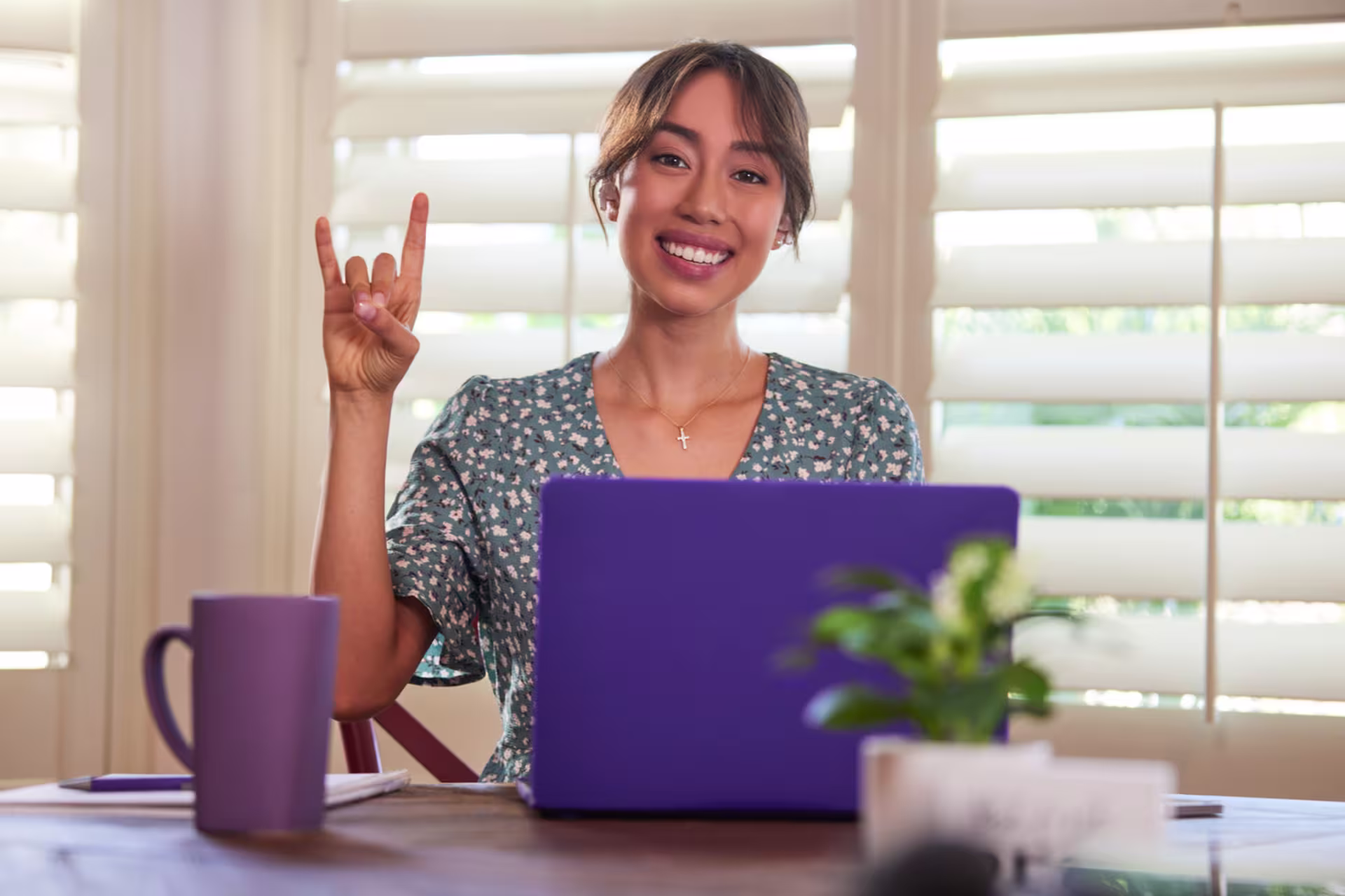 Woman smiling while reviewing student loans on laptop in kitchen