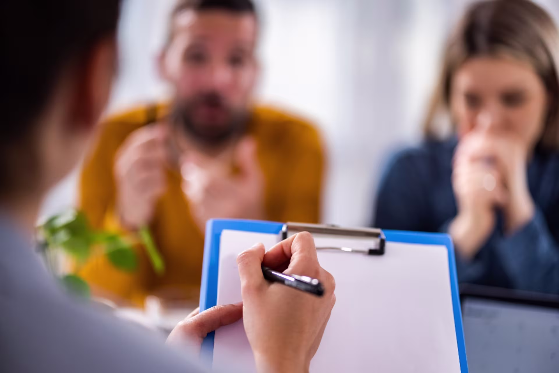Marriage counselor taking notes on a clipboard while with a couple