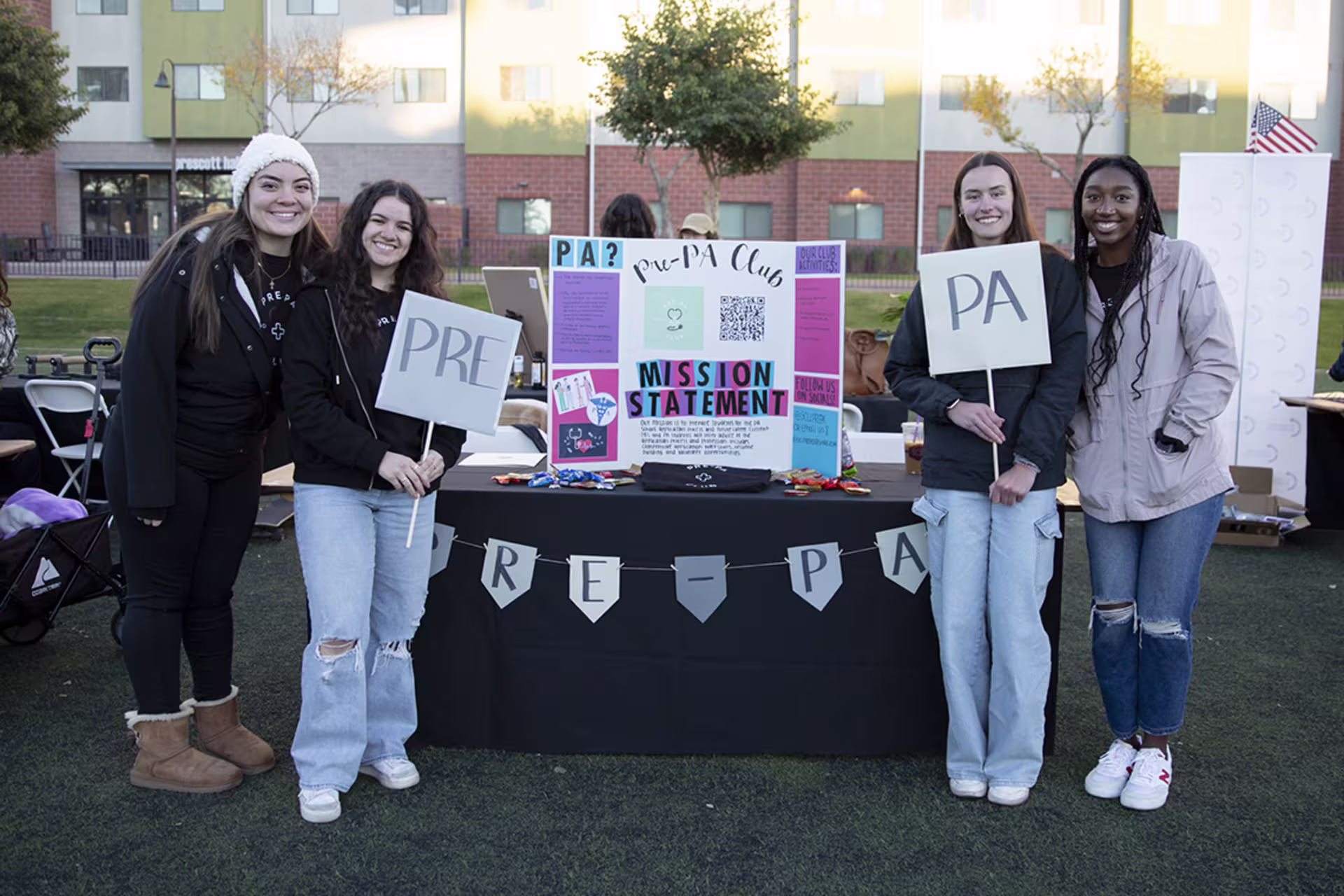 Female Pre-PA Club members at Spring Club Community fair smiling and posing for camera