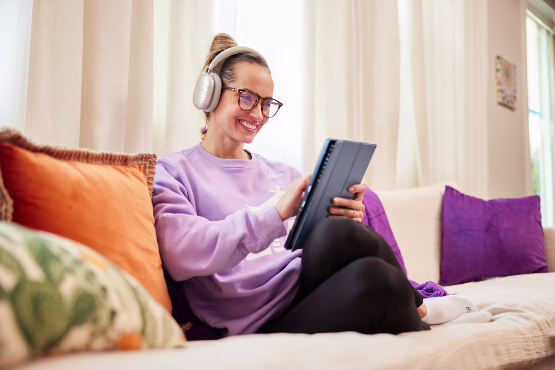 Woman sitting on couch and using tablet to apply for online courses