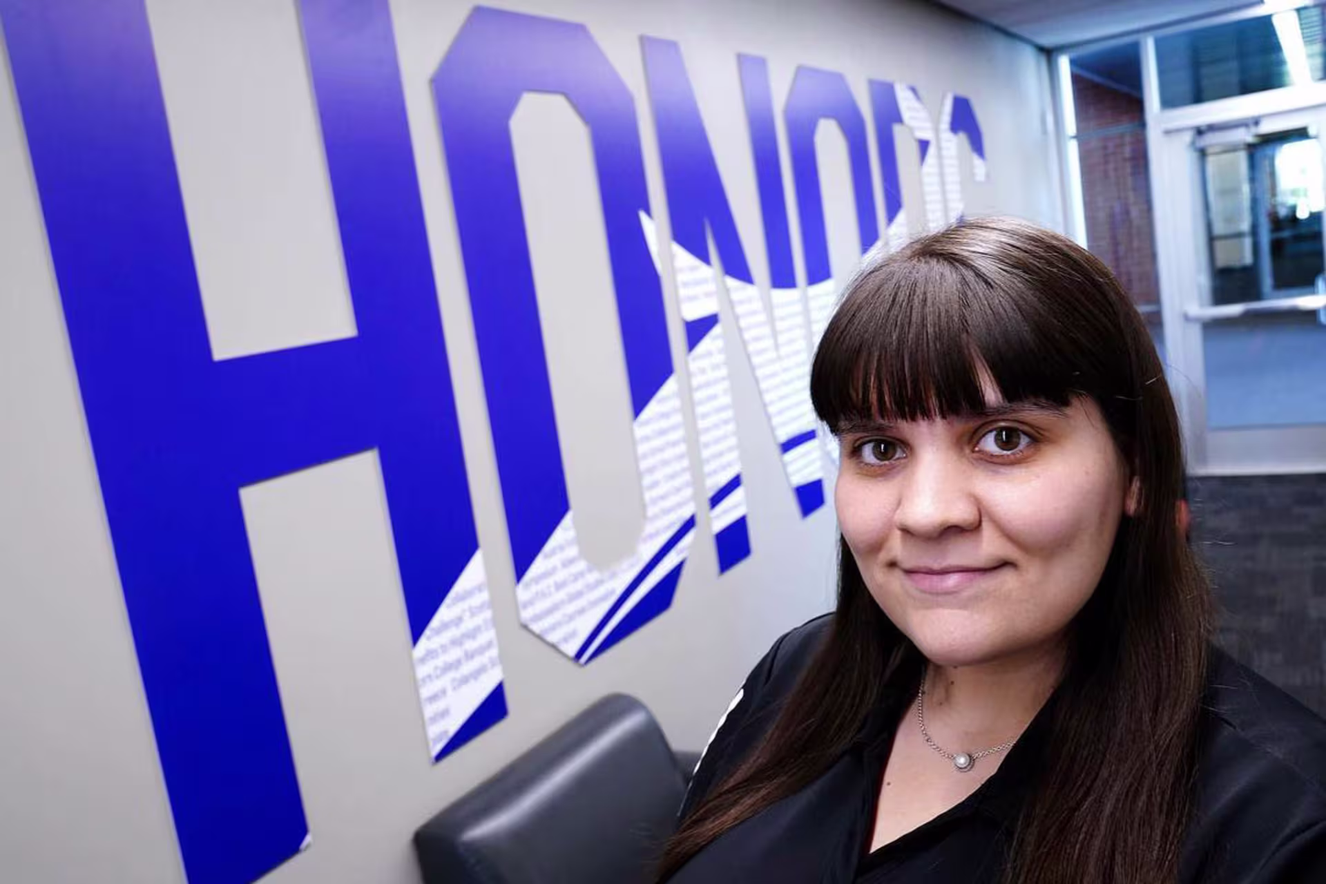 big honors letters in gcu purple on wall with staff member katalina ready to assist students