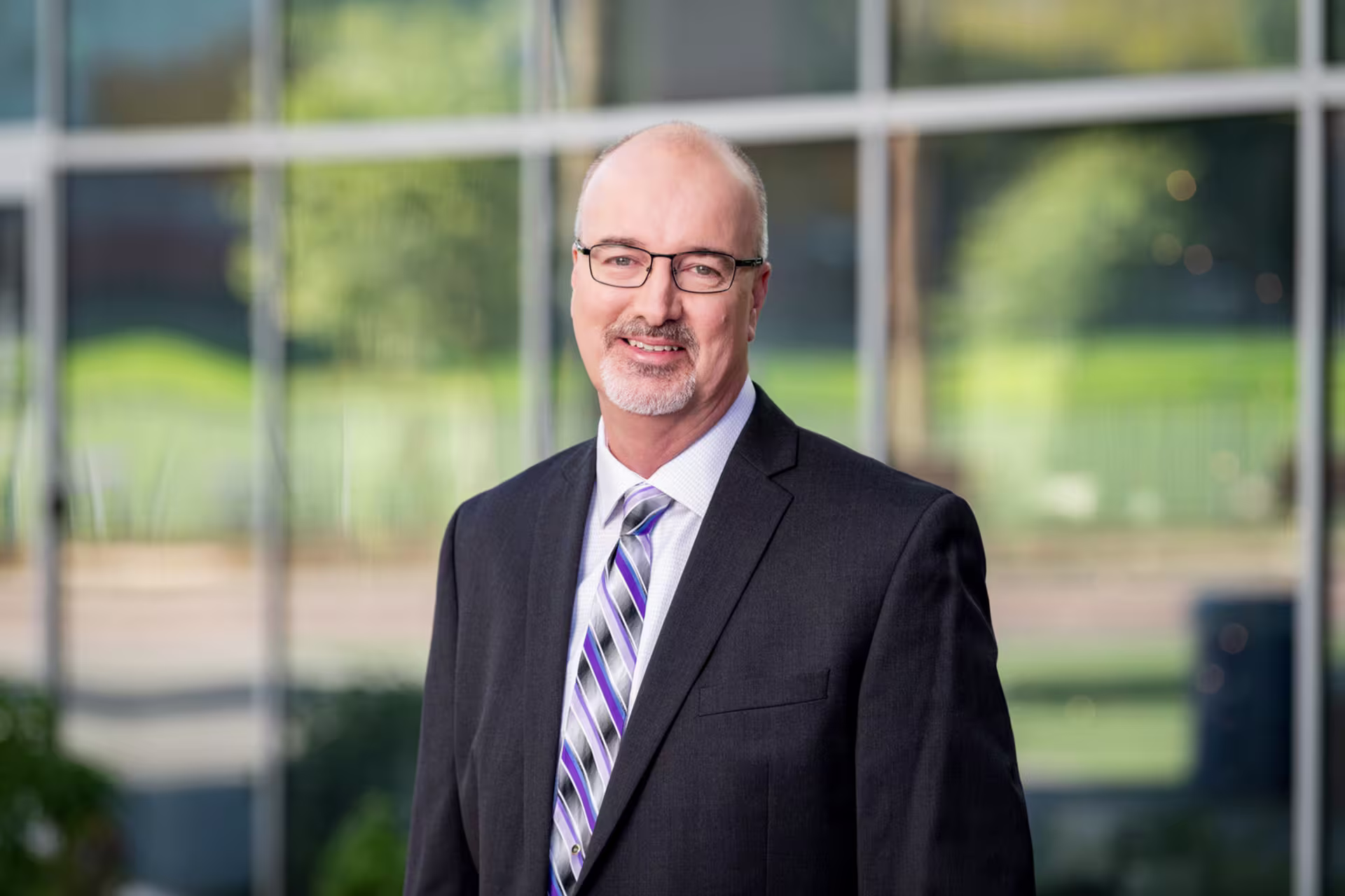 Headshot of Bob Romantic in front of building with windows for walls.
