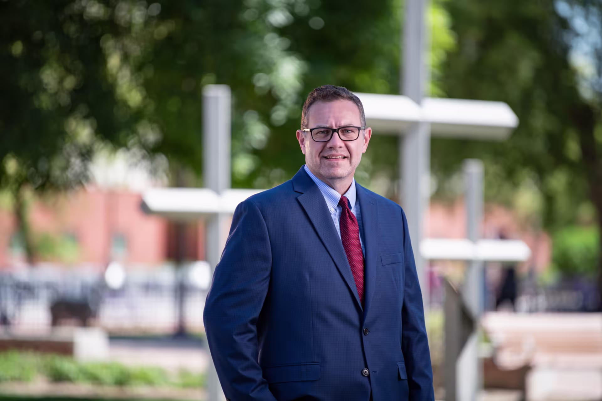 Headshot of Scott Greenberger smiling in front of crosses on college campus.