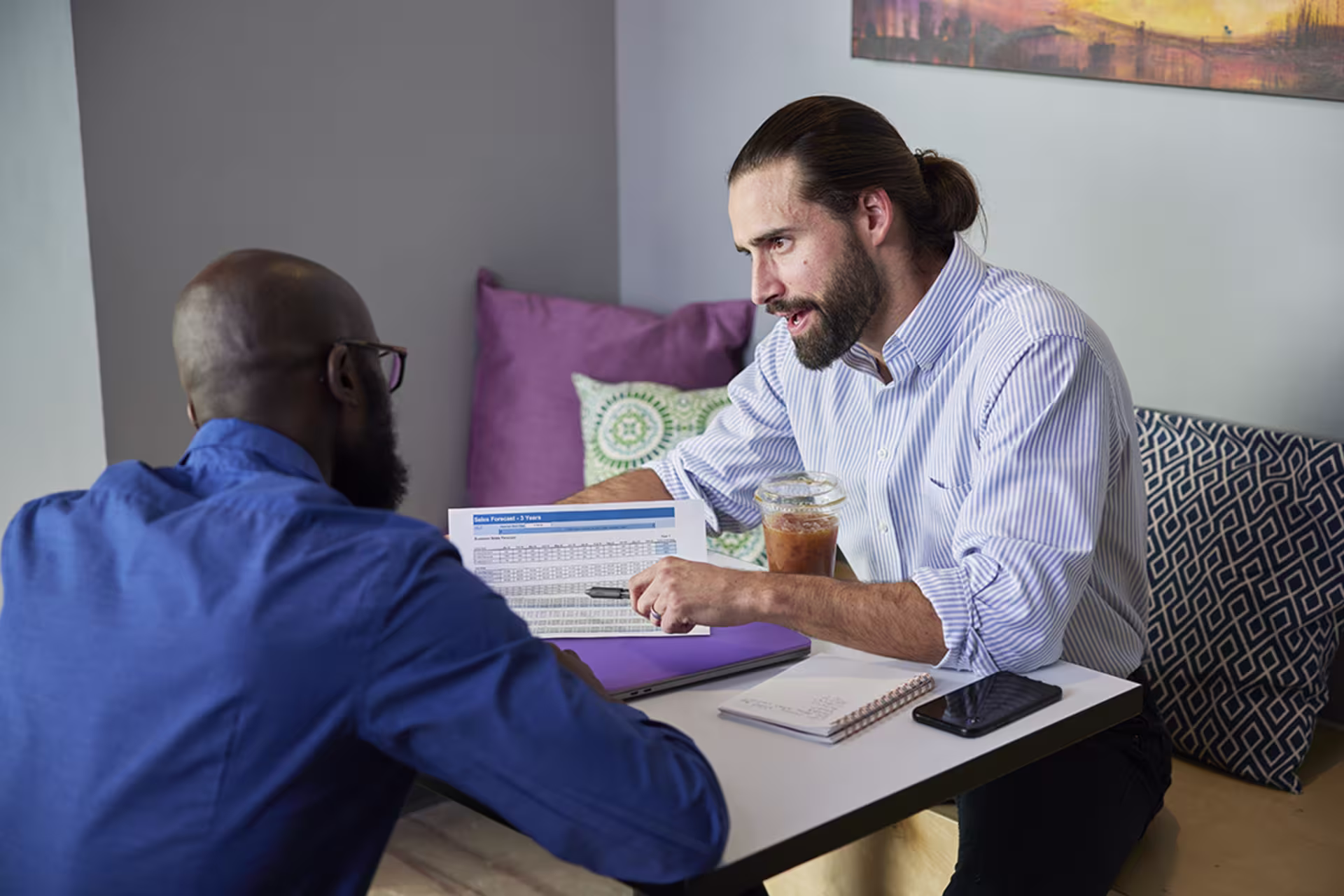 Male business students looking over report in coffee shop together