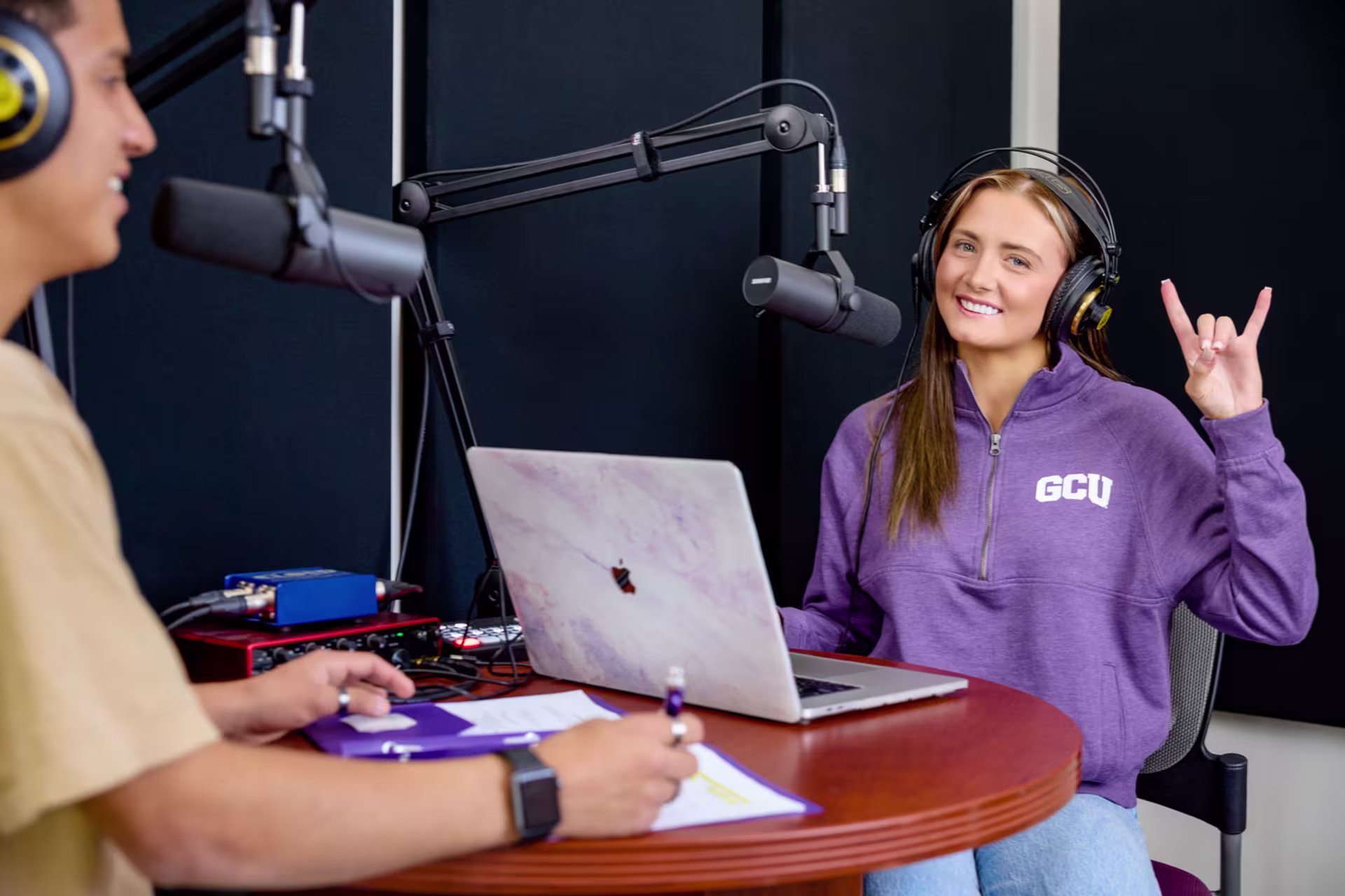 Female broadcasting major recording in studio with another male student