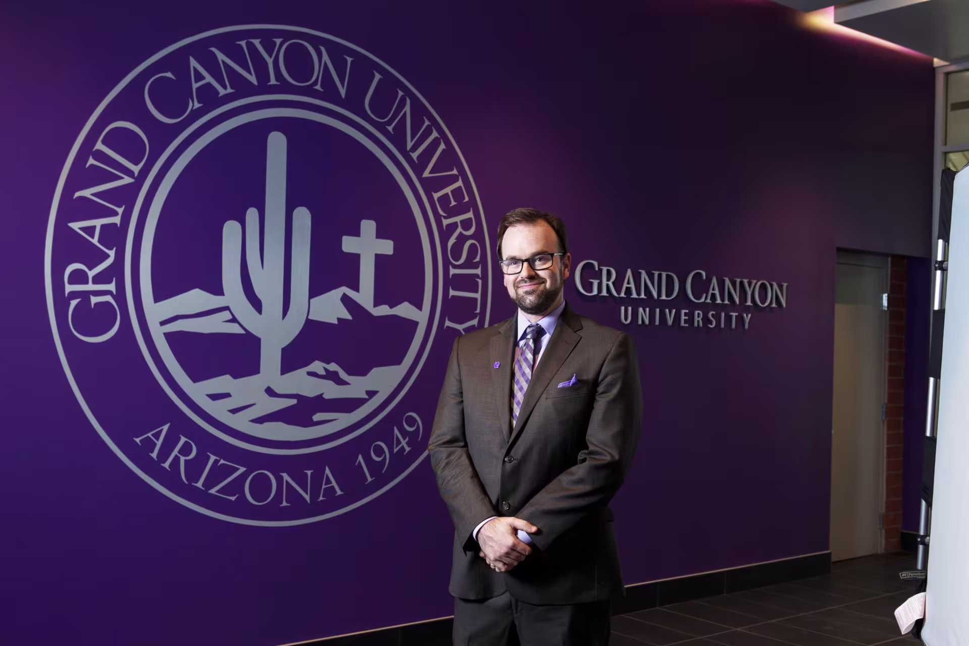 Headshot of Dr. Michael Berger wearing suit in front of purple painted wall.