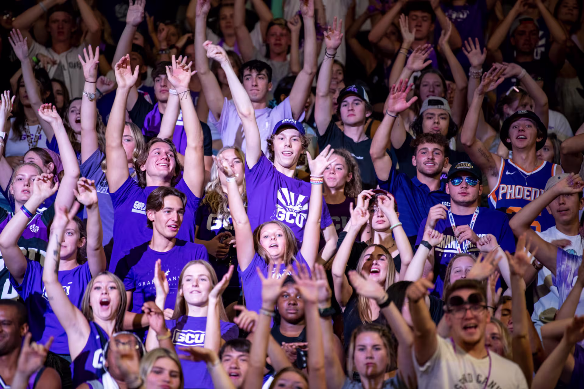 Students cheering and excited at a GCU event all wearing GCU purple with arms up