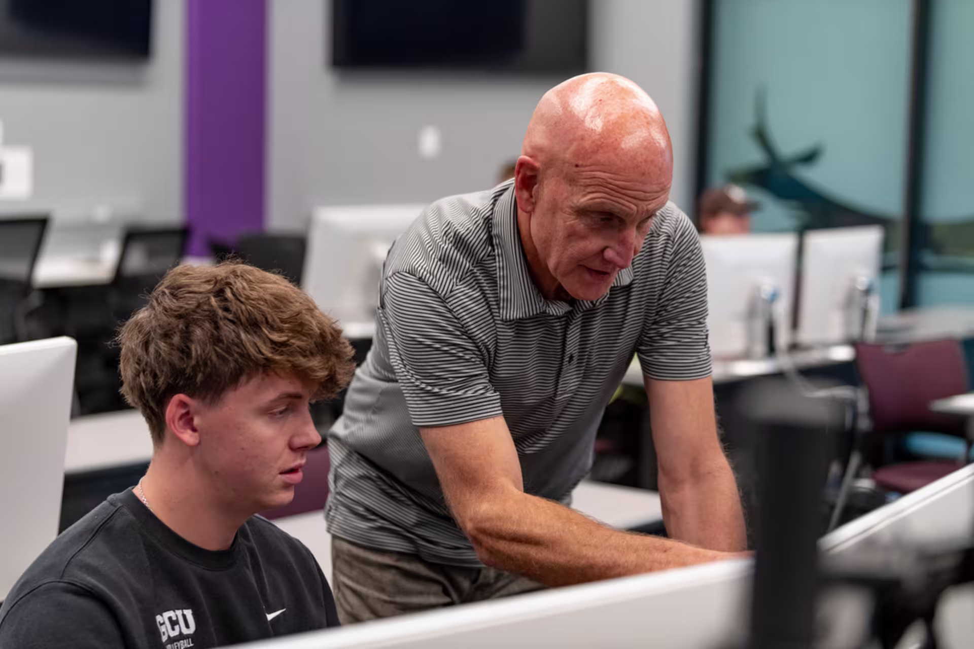 cybersecurity professor helps young male IT major student with computer programming concept