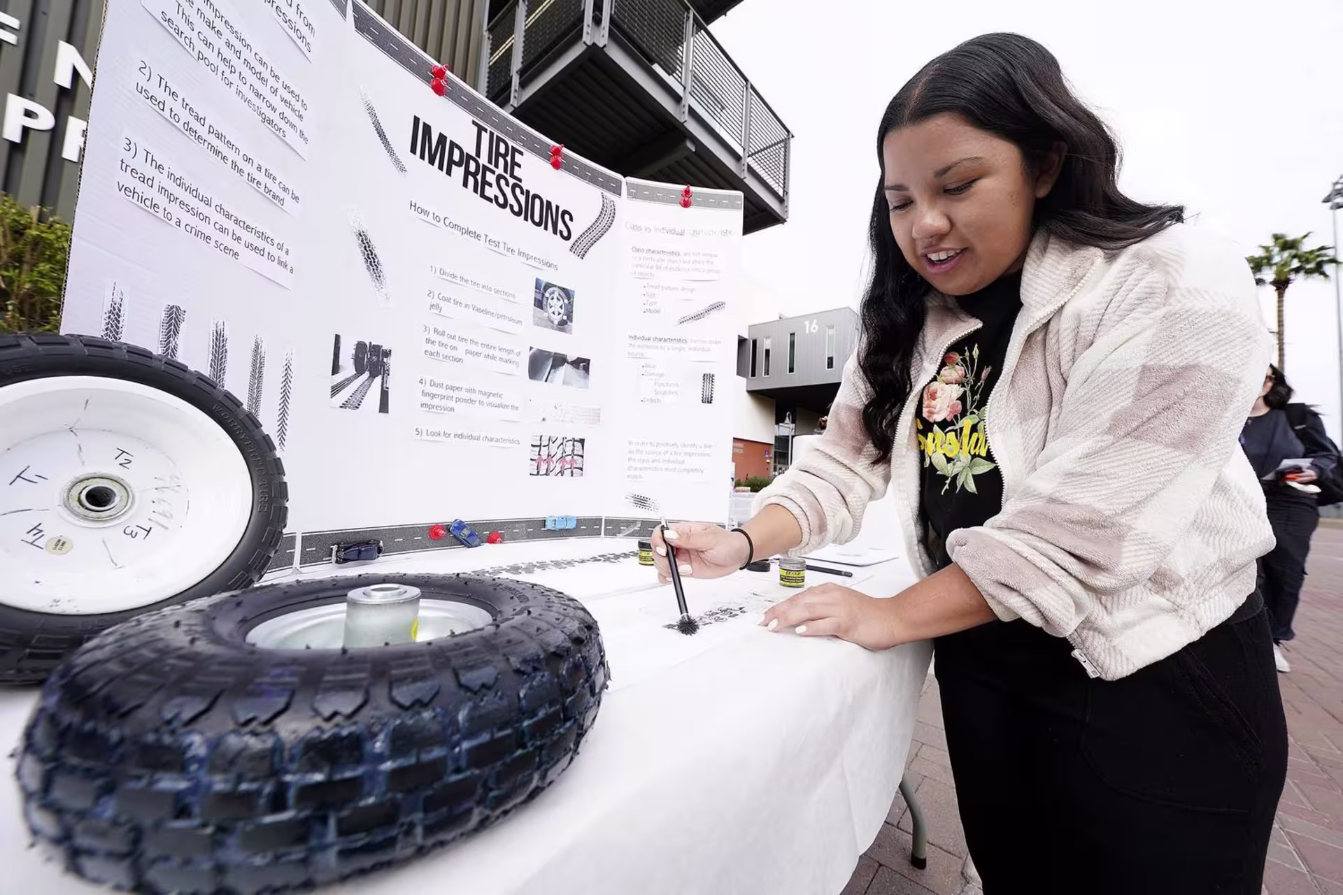 Female physical science minor giving tire impression demo at showcase event
