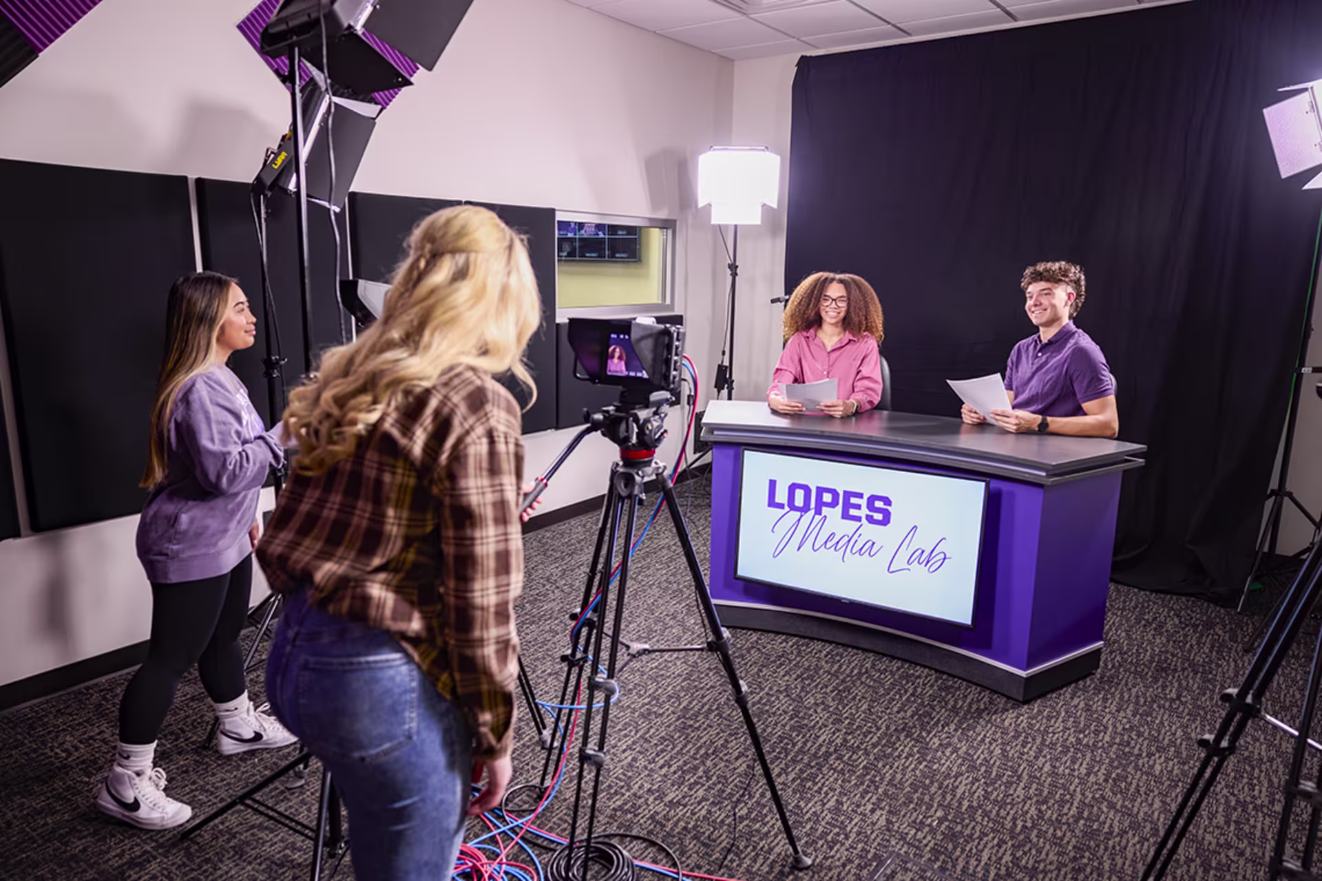 Female and male students being broadcasted in studio via female students videoing them