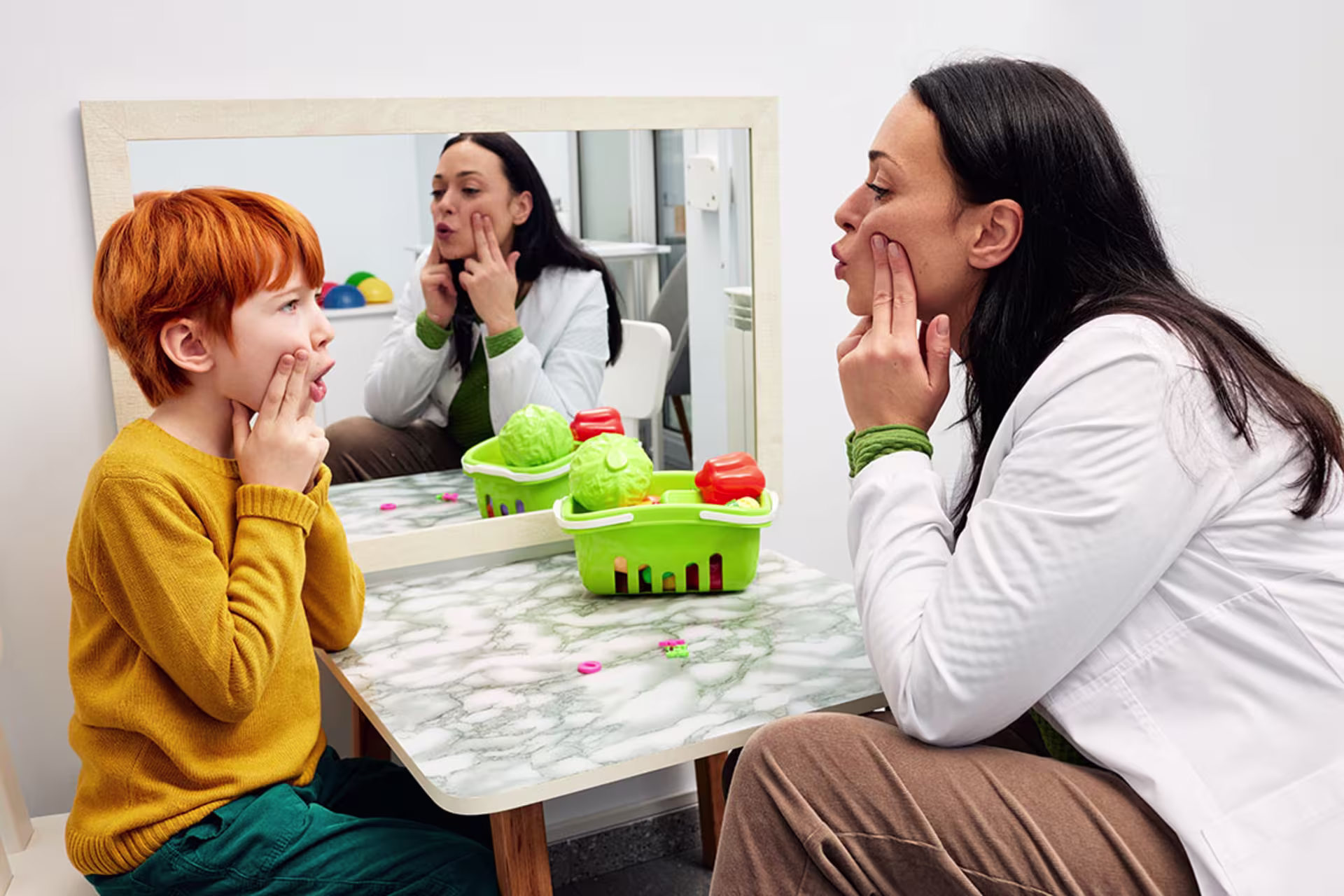 Female speech pathologist working with young male client on pronunciation