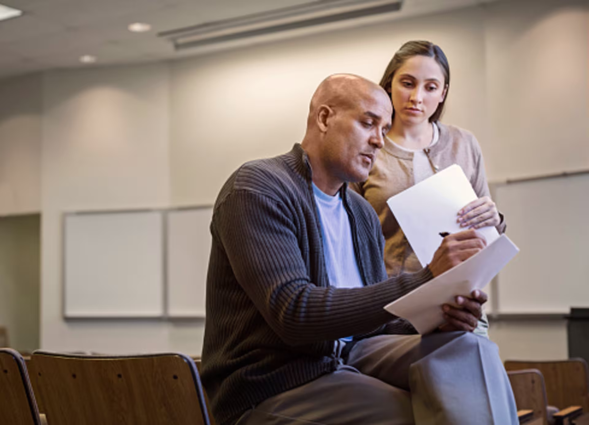 student and professor speaking and reviewing papers