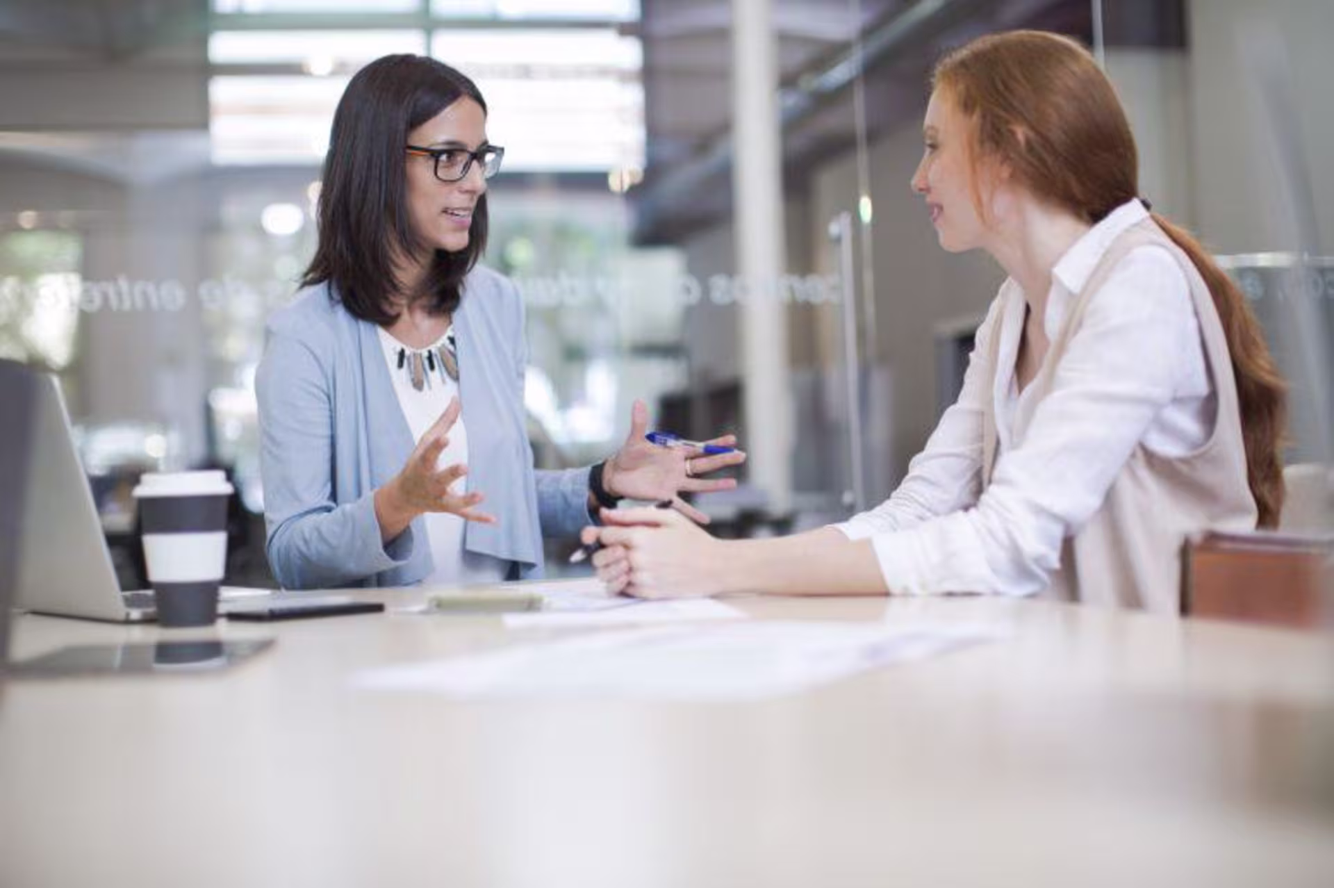Life coach sits with a client in conference room with glass walls
