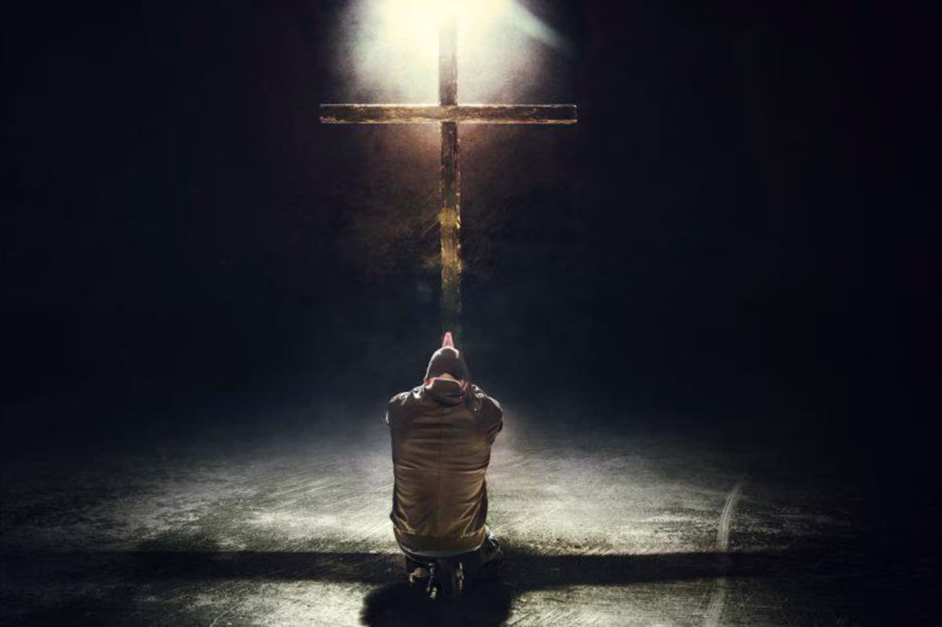 person kneeling and praying at the cross