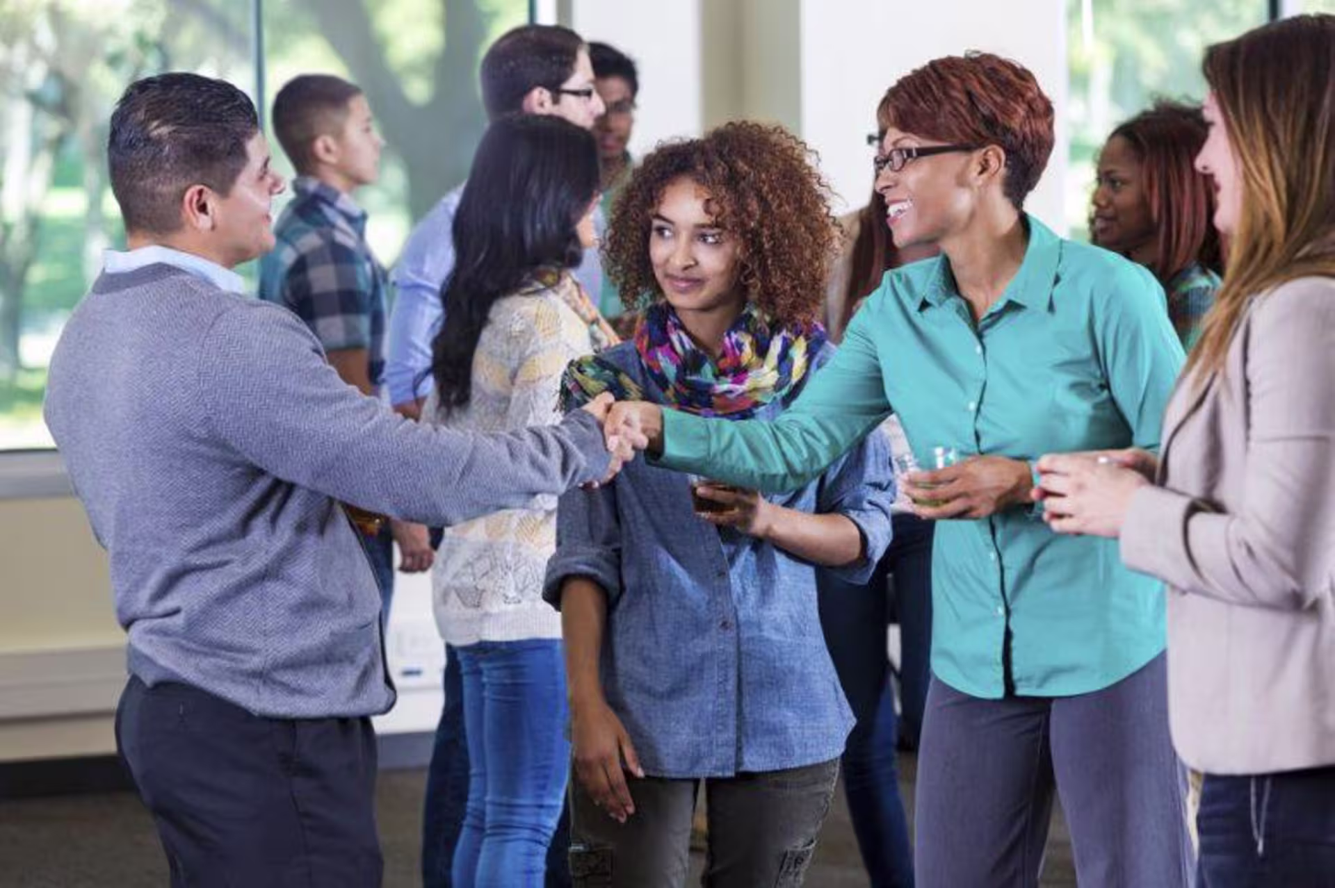 Two people shaking hands around other people