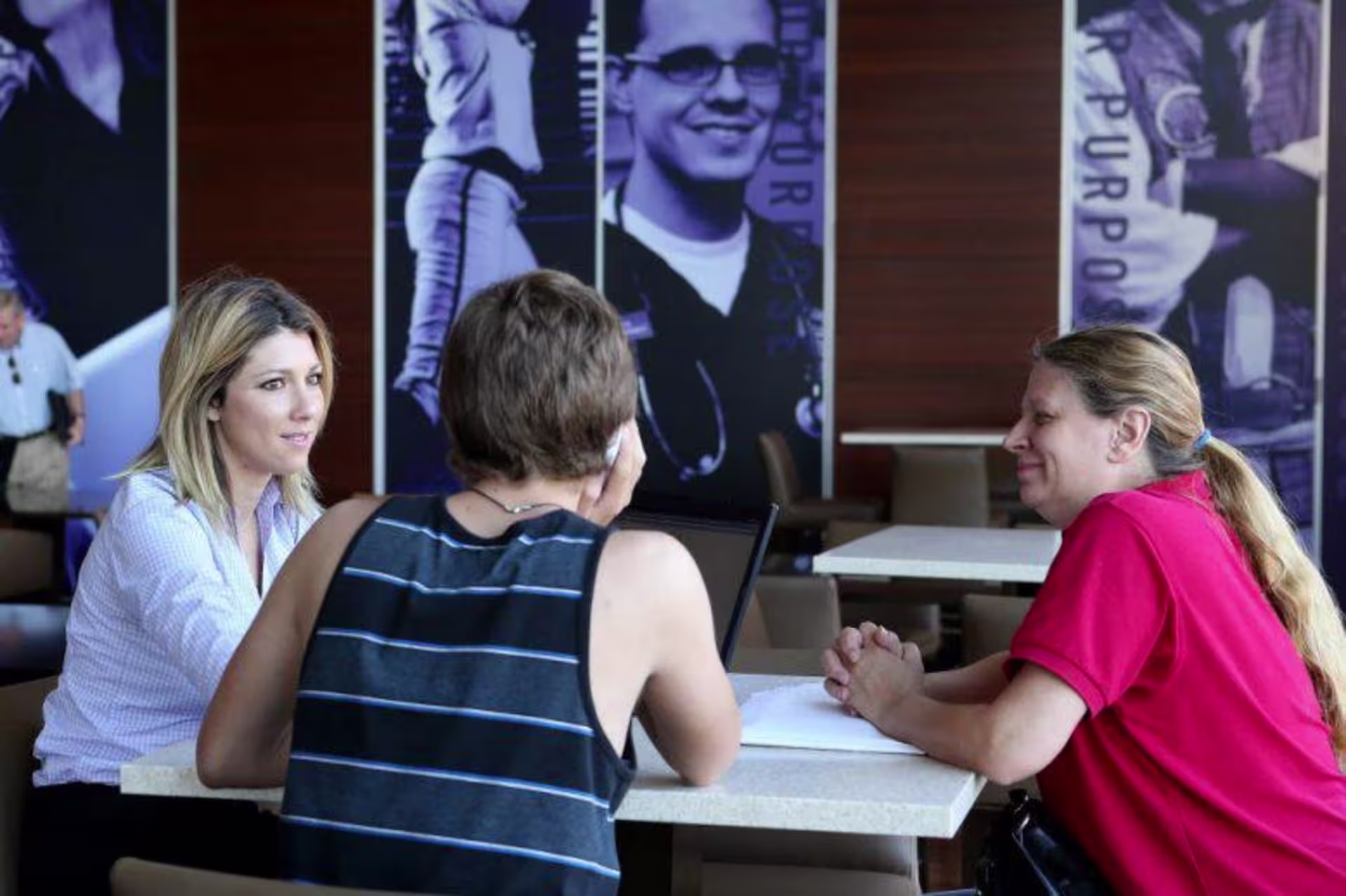 three people sitting around a table and talking