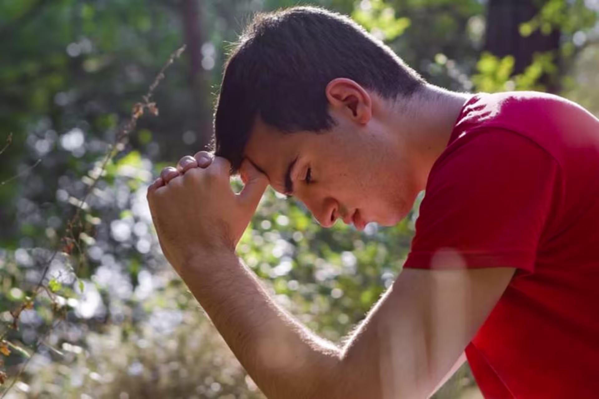 A man hanging his head in the wilderness