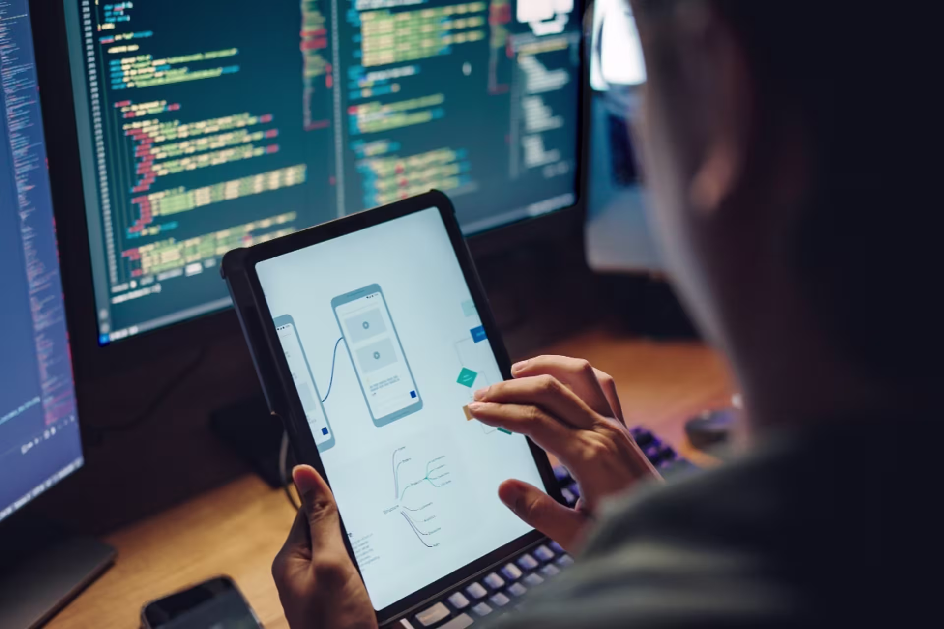 Female app developer working on an iPad with a computer code in the background.