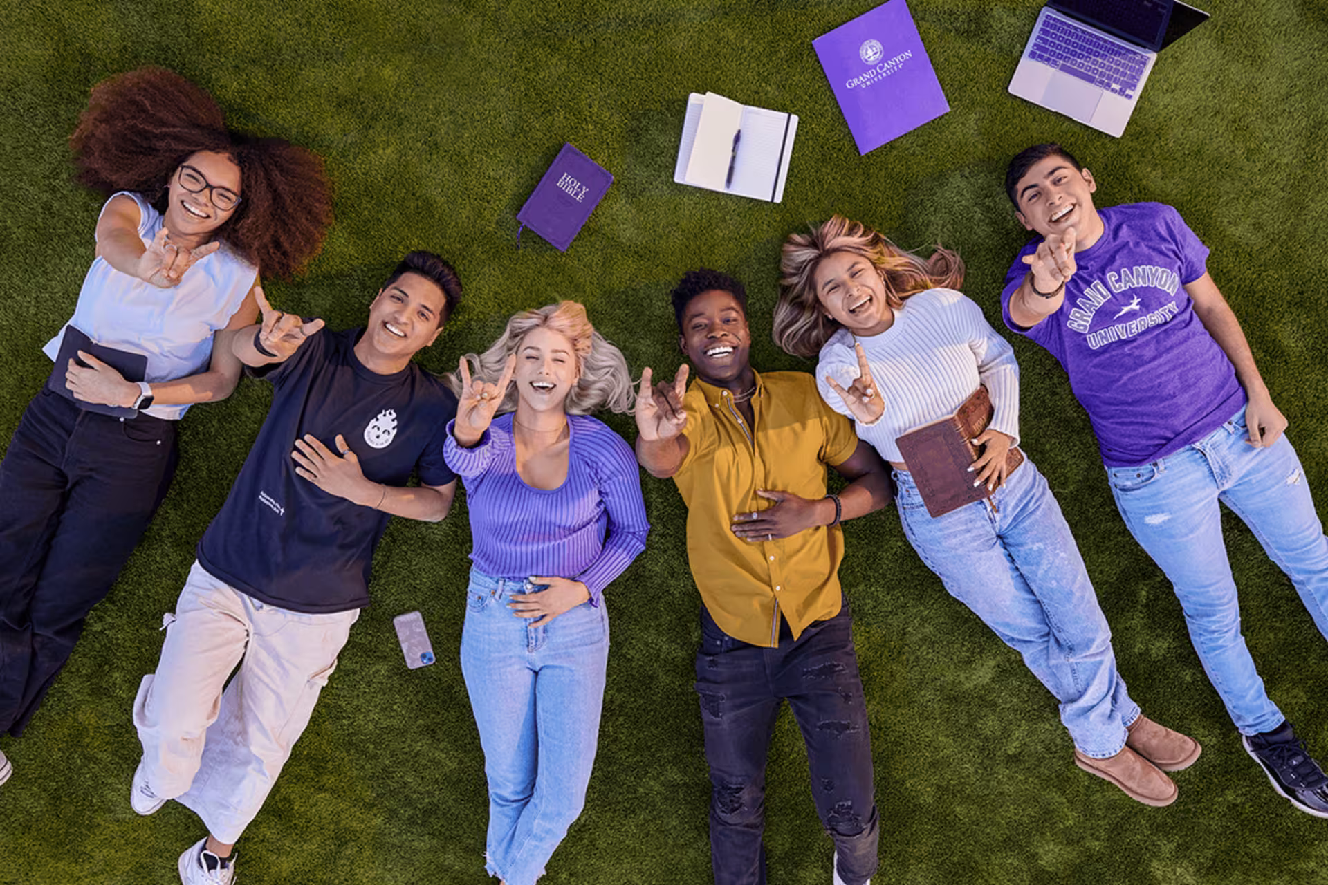 group of students laying on ground smiling for camera.