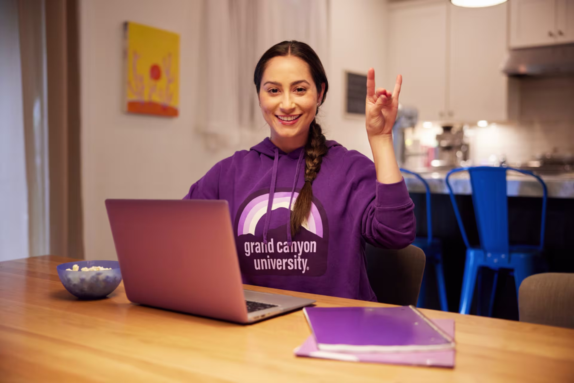 Mental health counseling student in a GCU sweatshirt working on coursework on a laptop.