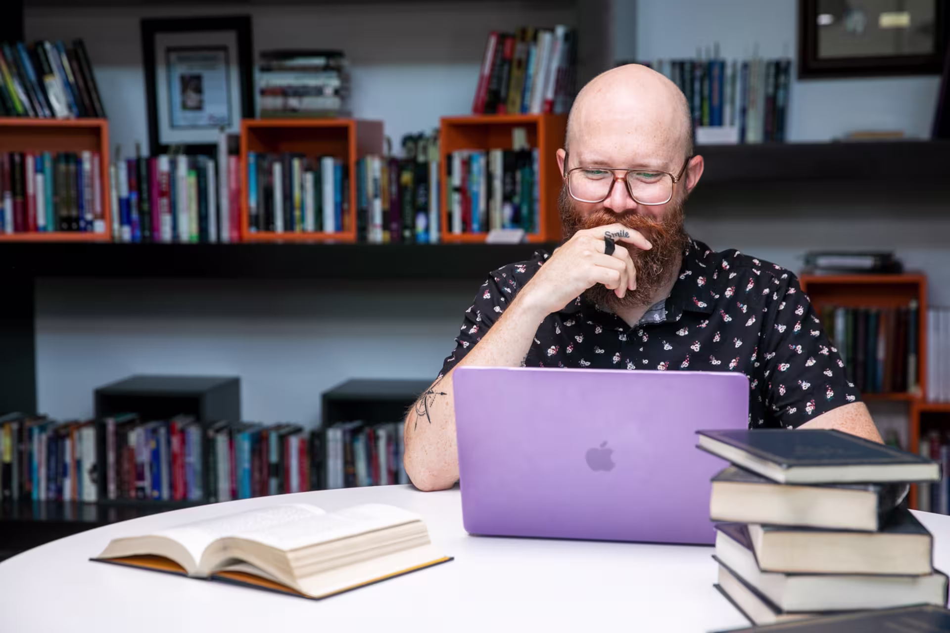 Online history student working on a purple laptop in a library setting.