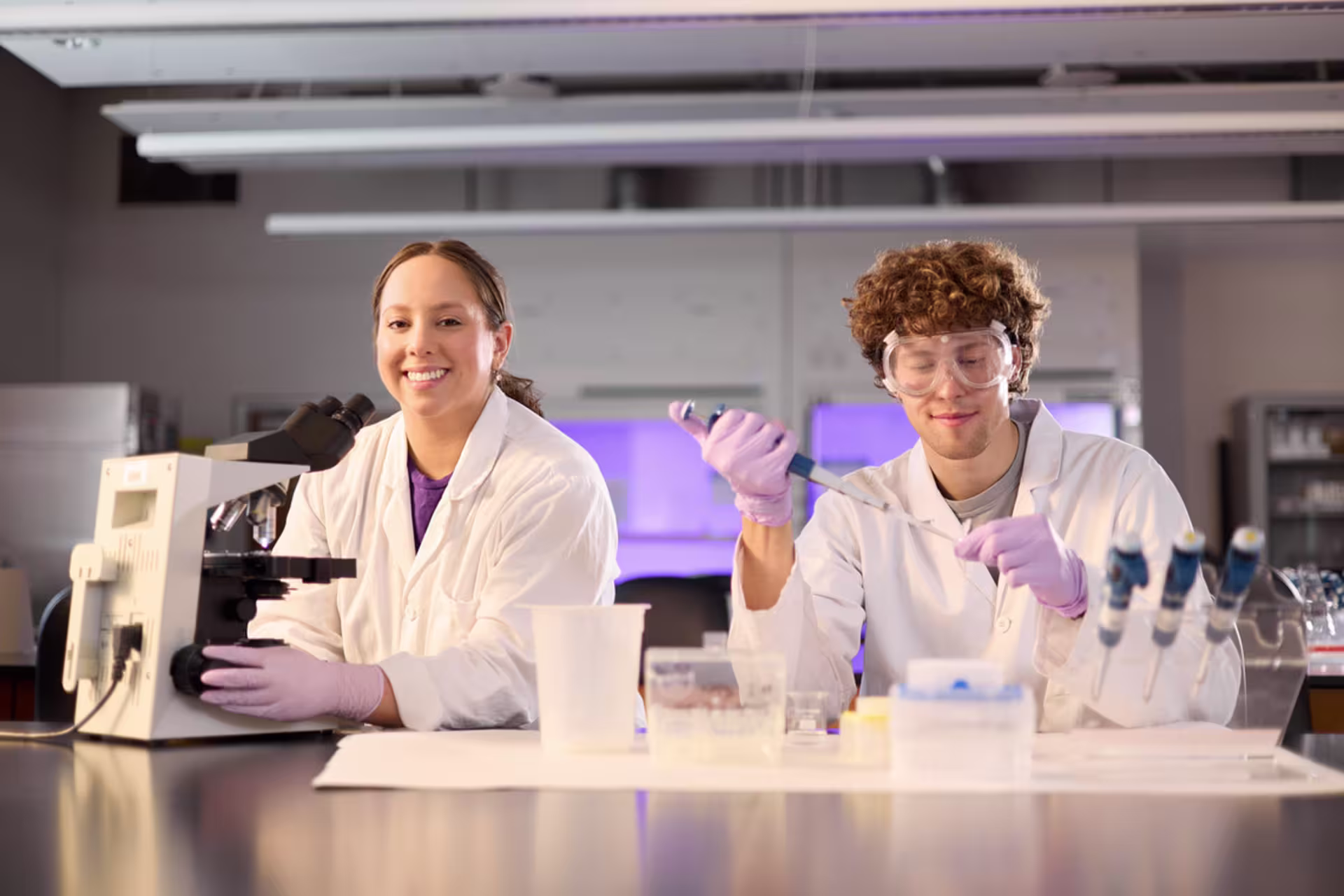 Two forensic science students in gloves in a laboratory setting.