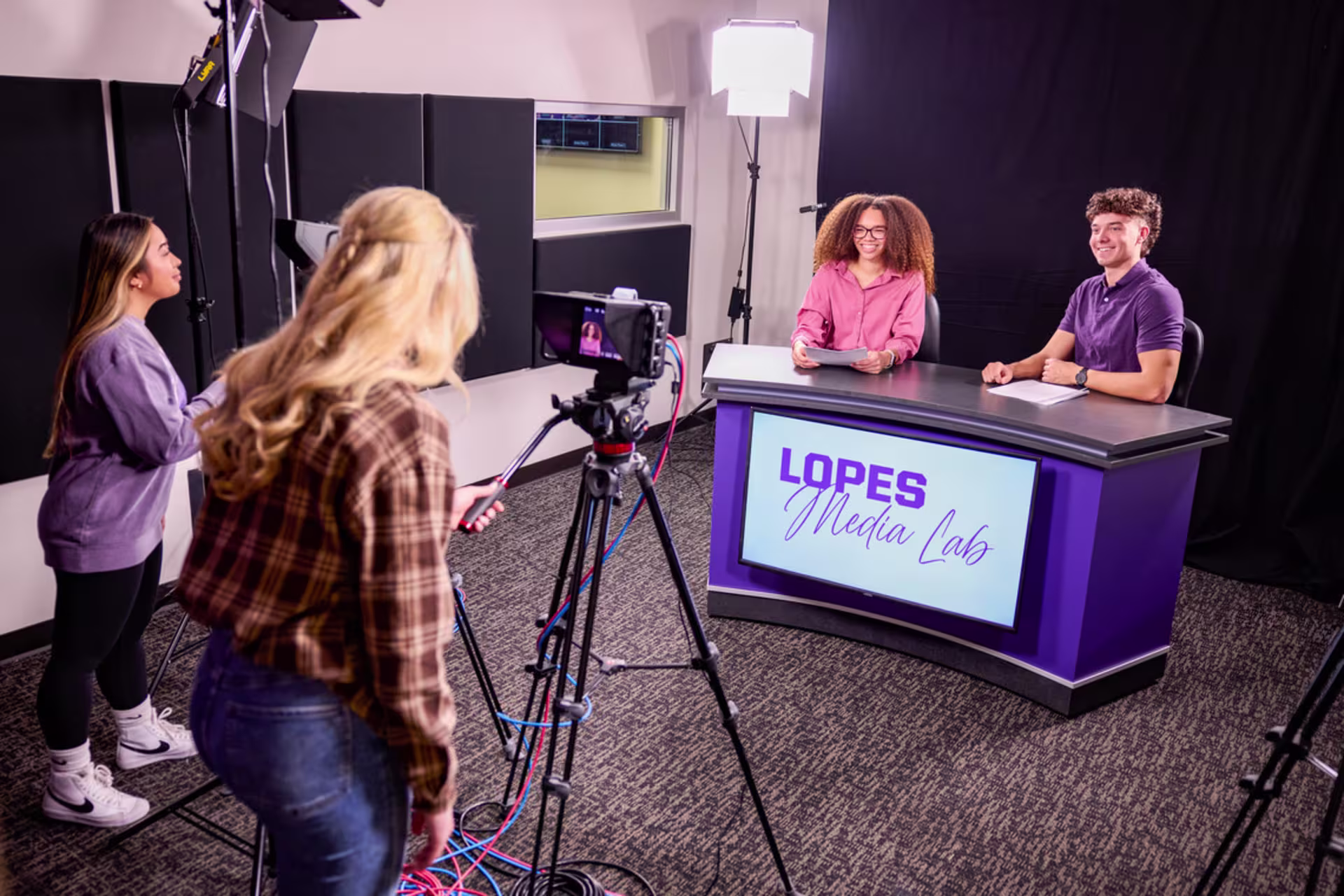 Digital film and video production students smile on set in the Media Lab.
