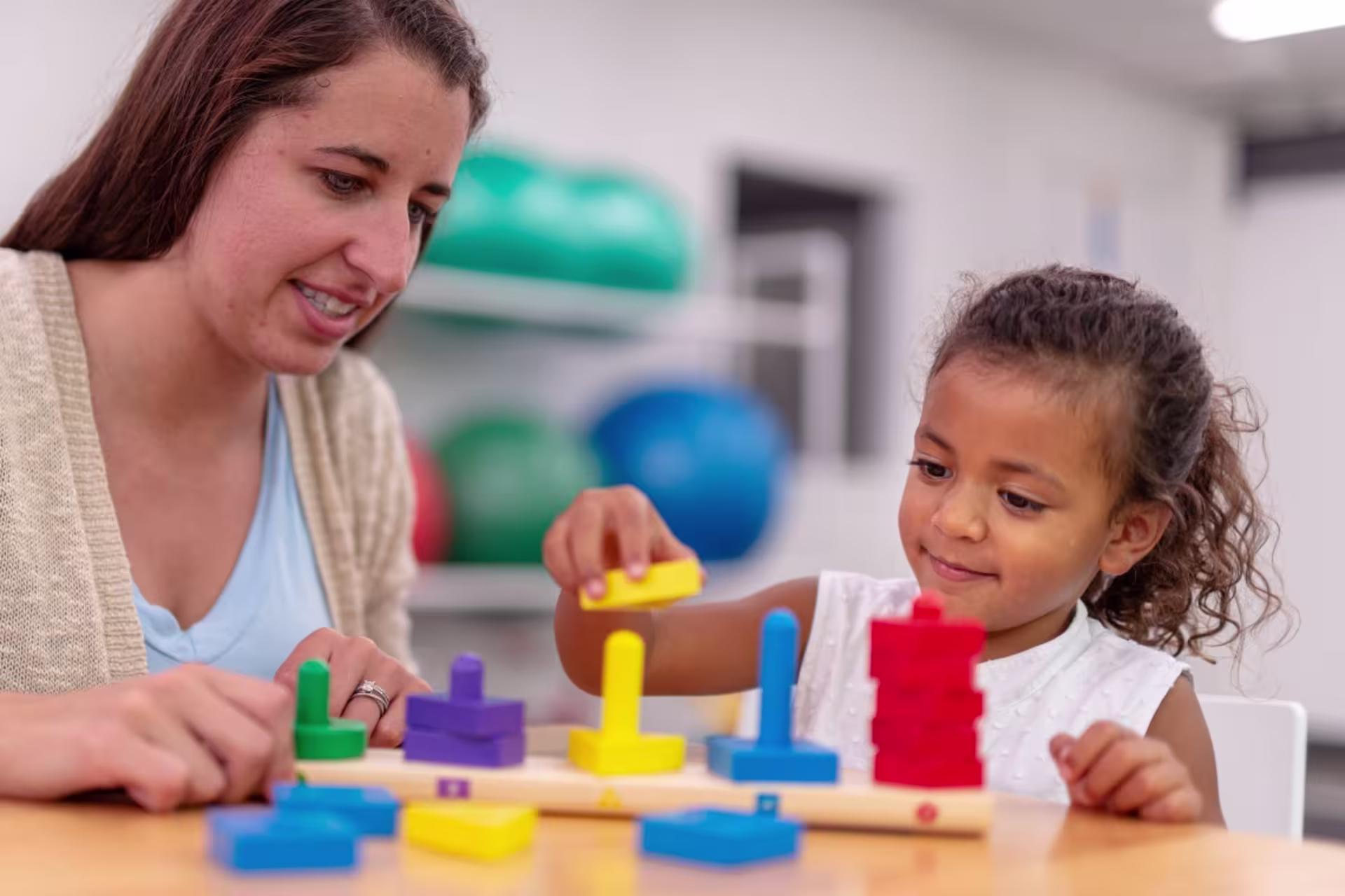 Female pediatric occupational therapist stacking blocks with a child.