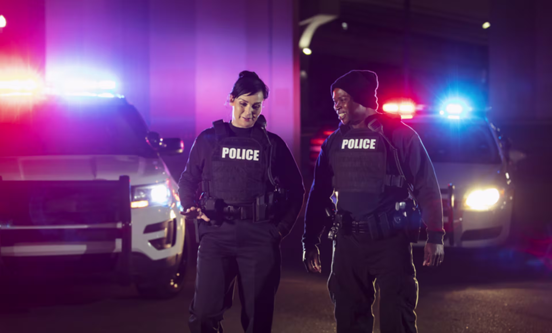 Police officers talking and walking near police cars