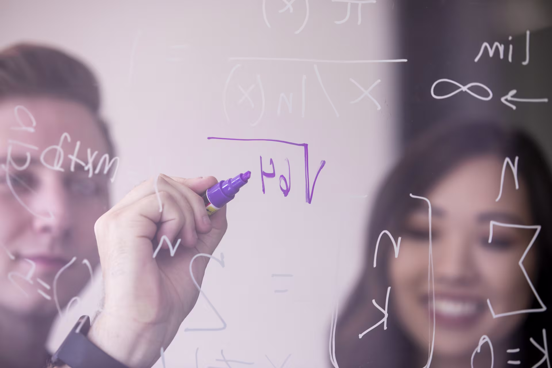 Two GCU math teachers writing on glass wall