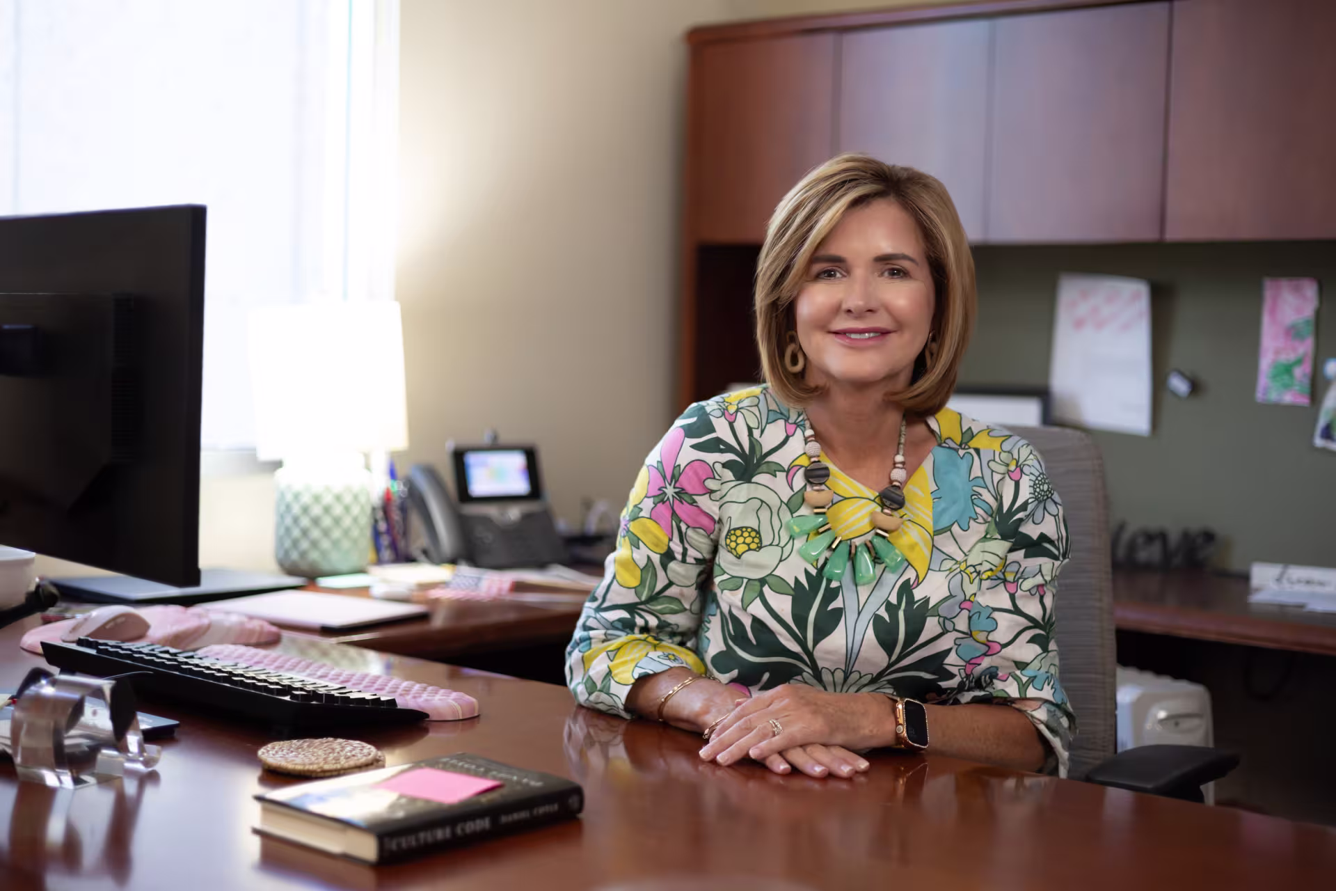 Female psychiatric mental health NP smiling at desk in office