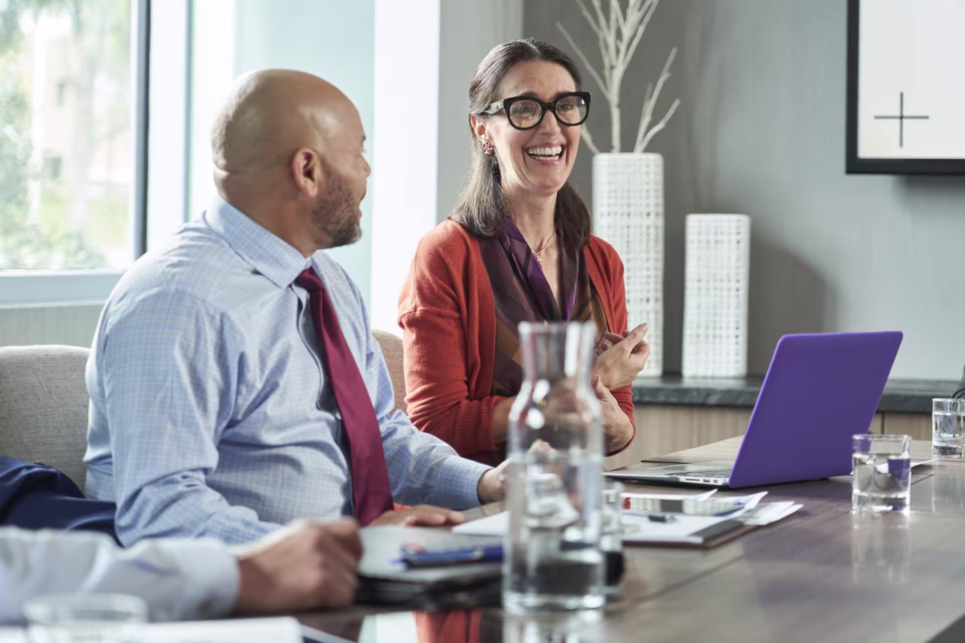 Male and female marketing professionals laughing while working in office
