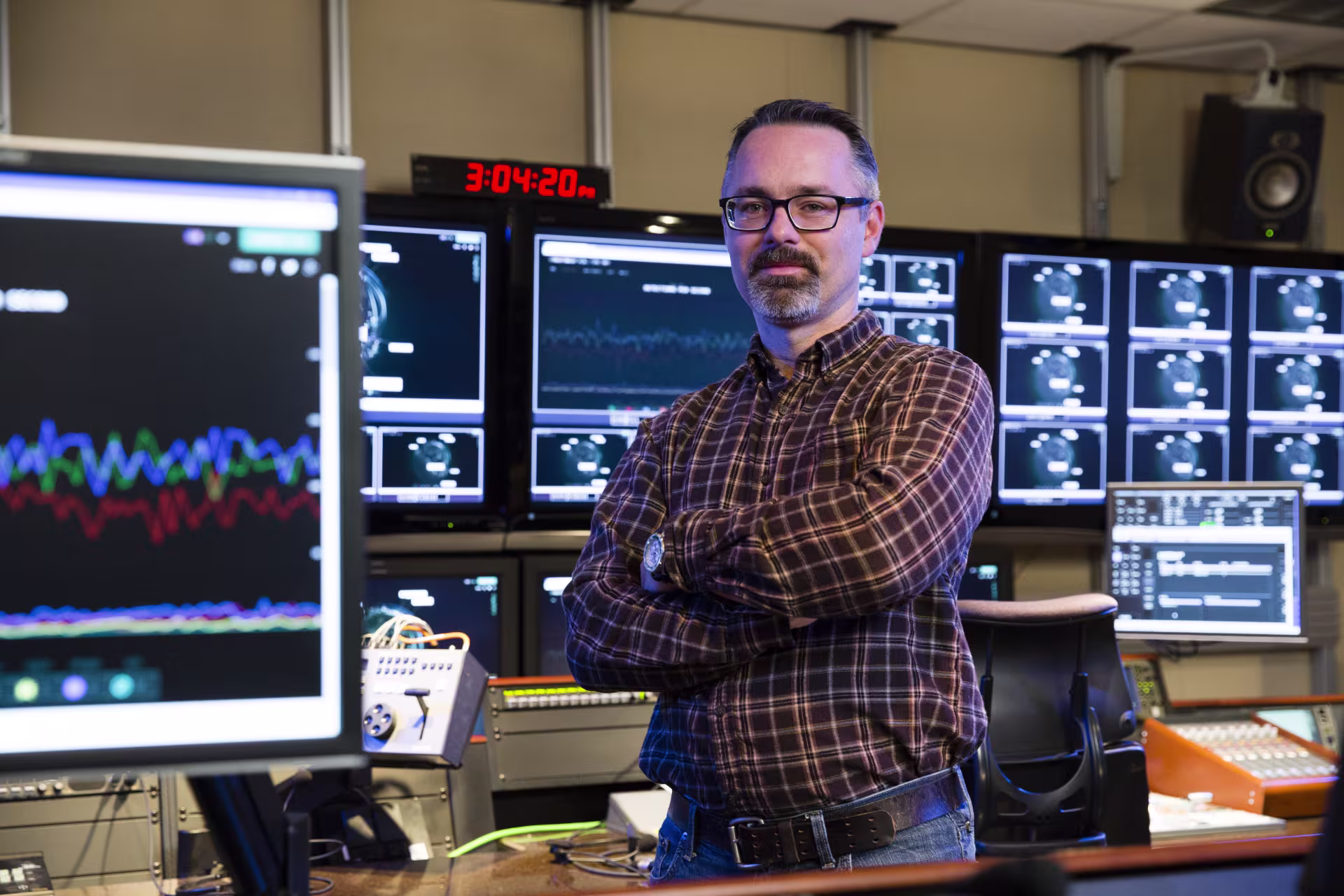 Male business information systems professional smiling in front of monitors