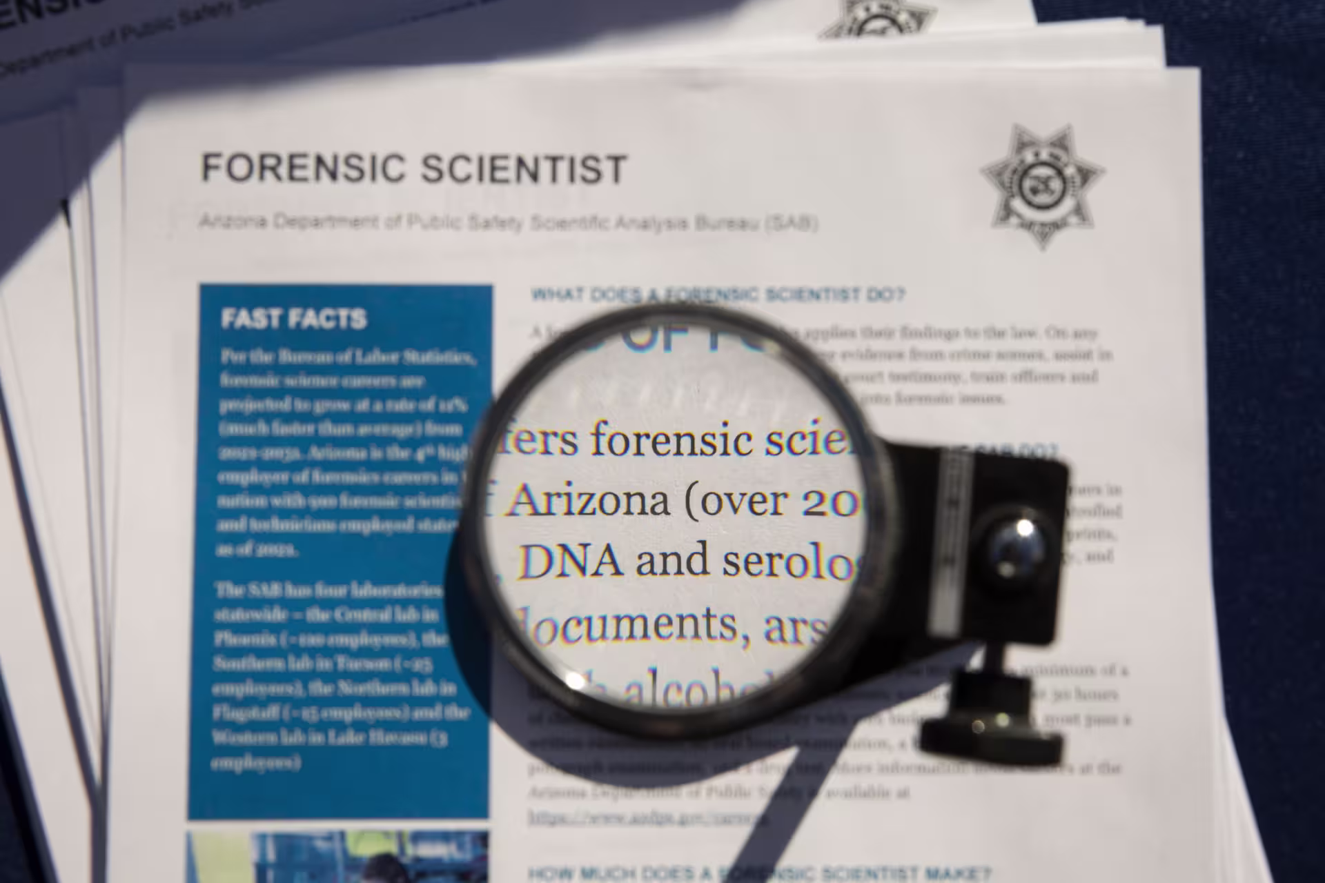 Close up image of magnifying glass hovering over forensic science newspaper