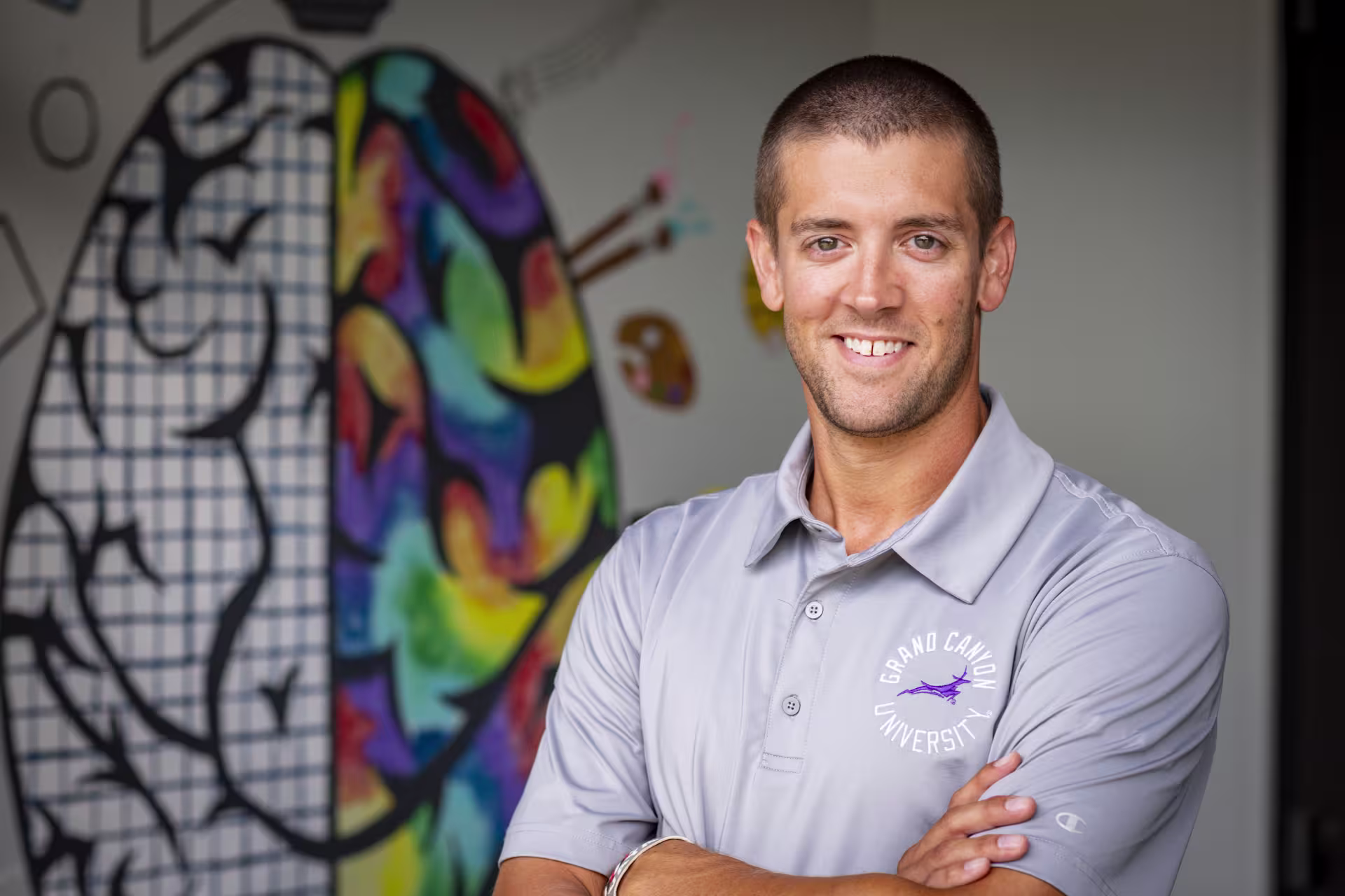 Headshot of male nurse educator smiling in front of brain painting on wall
