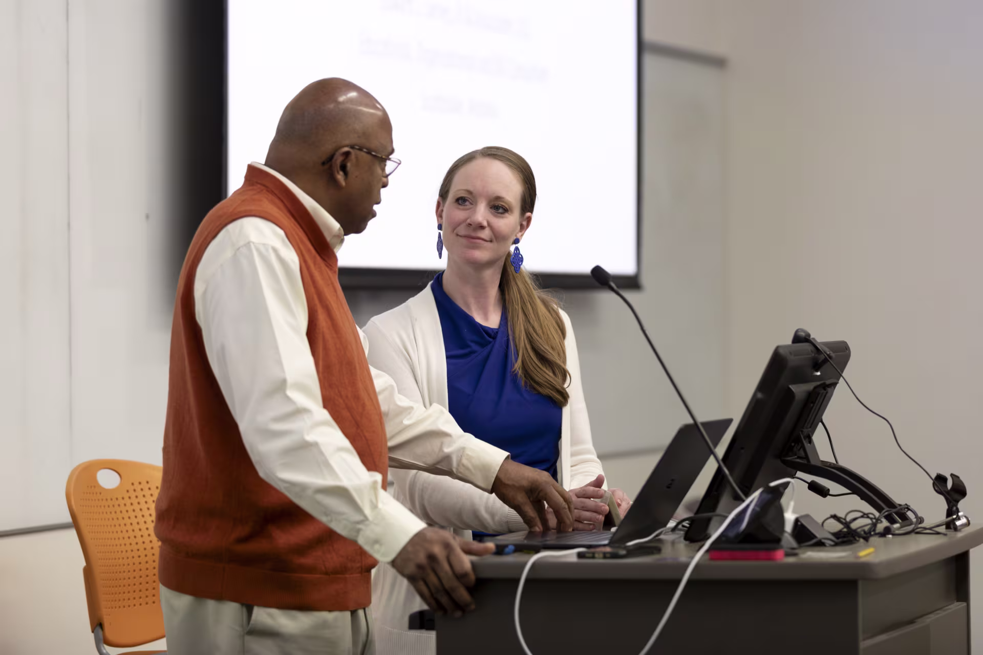 Male and female industrial organizational psychology instructors speaking at podium