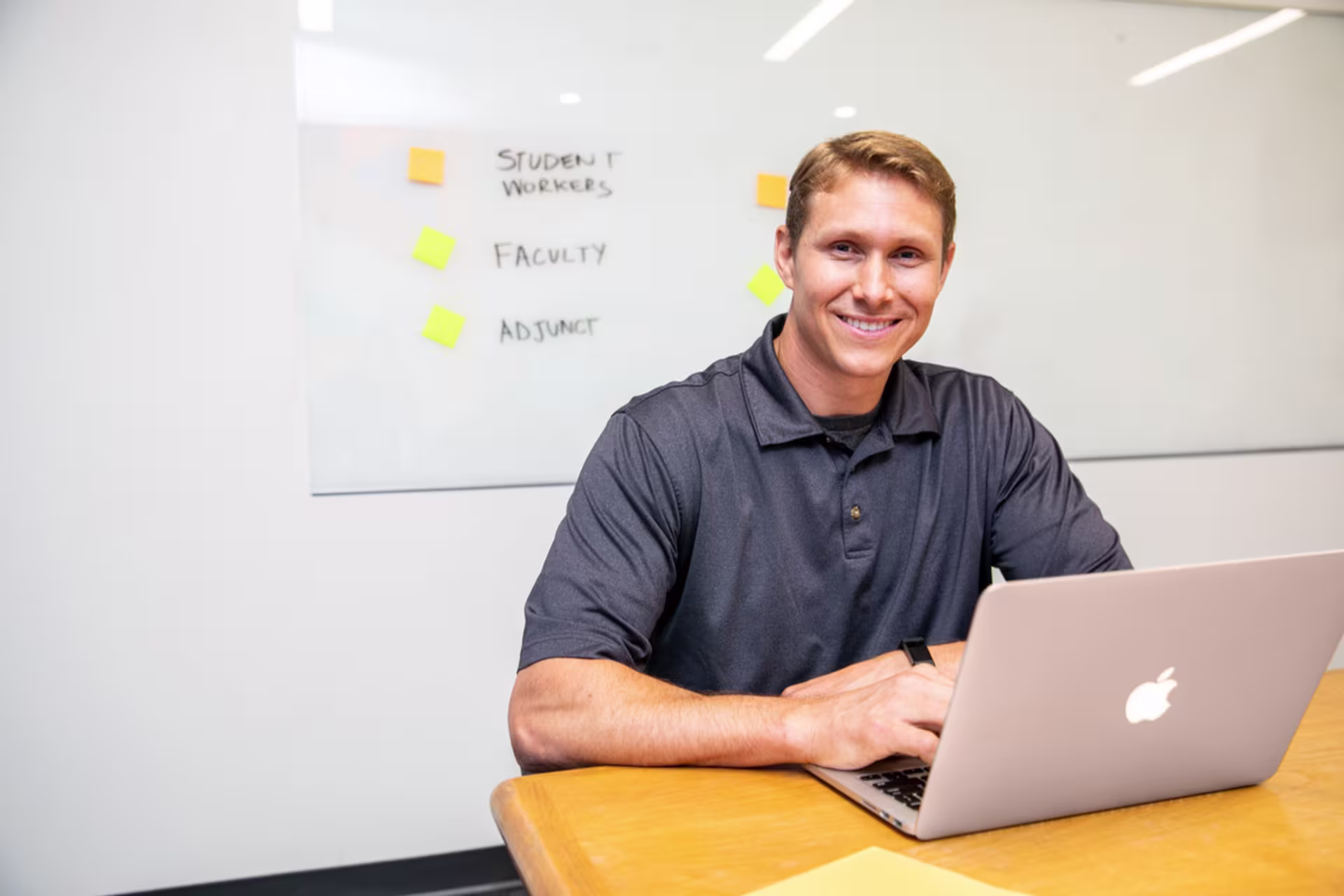 Strategic HR management student working on a laptop and smiling.
