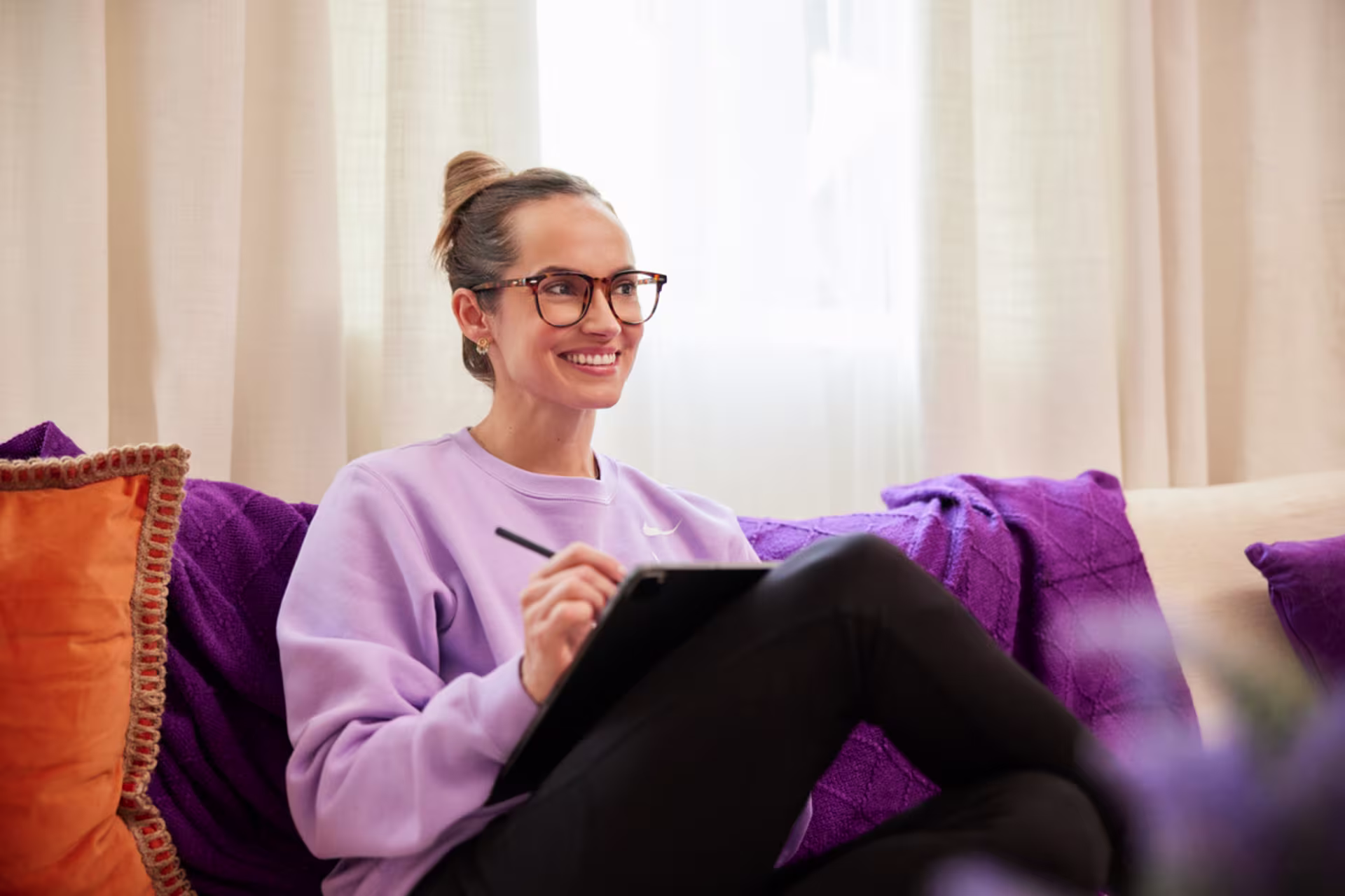 Female engineering management student taking notes on a tablet from home on a couch.