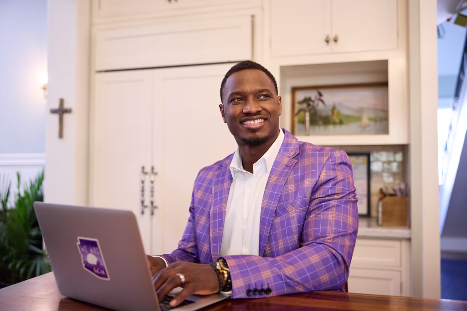Online systems engineering student in purple suit working on a laptop from home.
