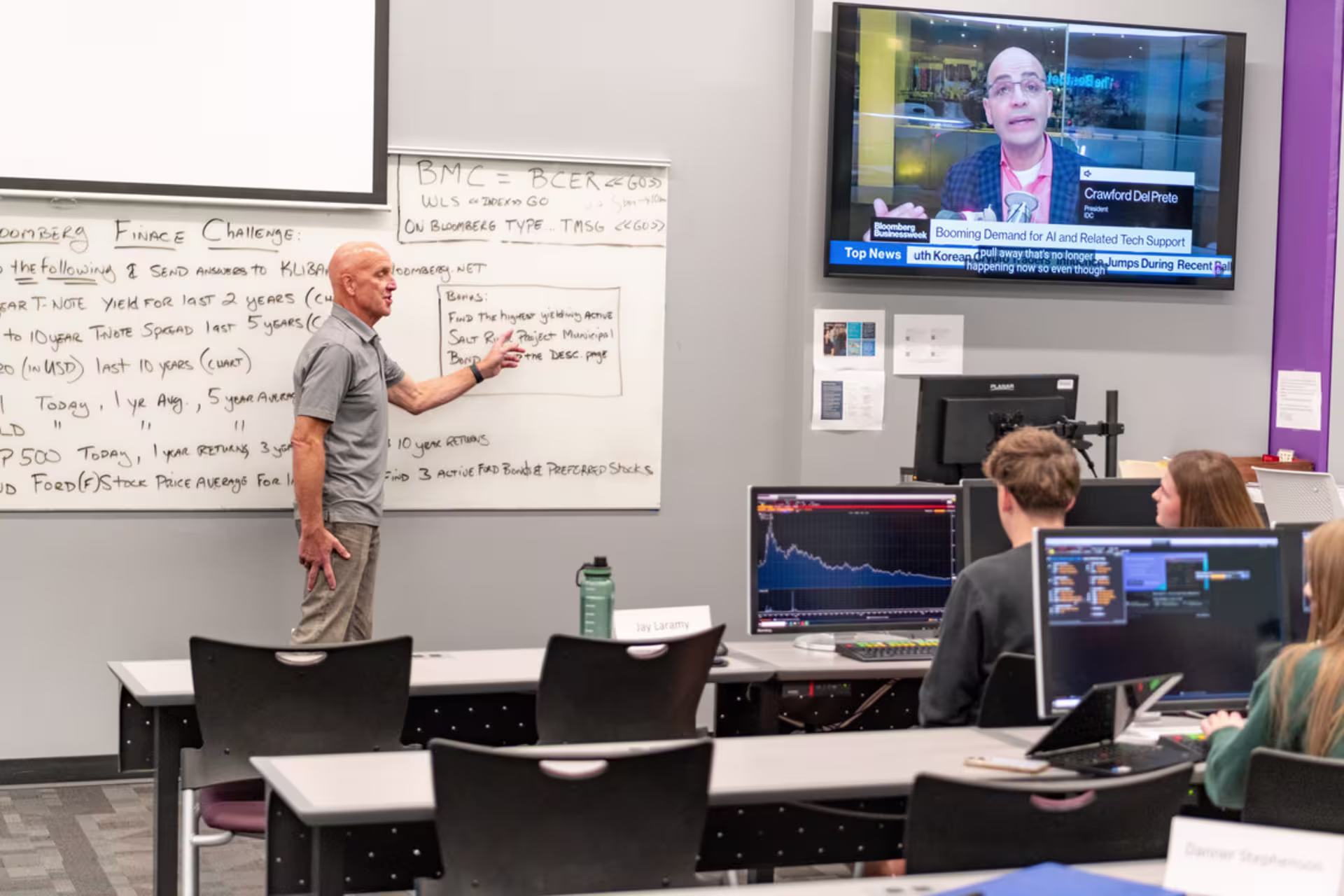 A finance professor teaches in front of a class of students.
