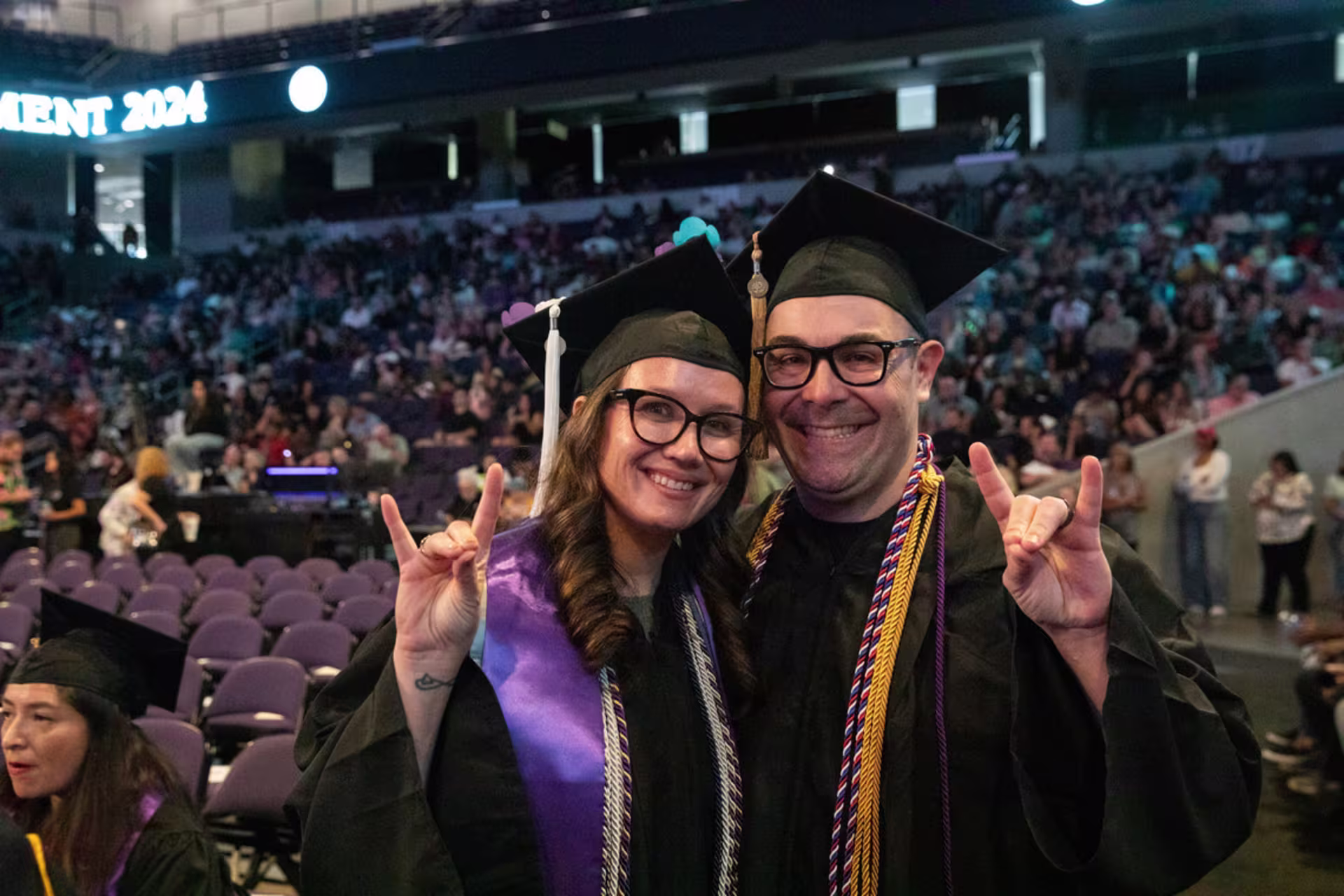 Two GCU graduates throw up lopes at a graduation ceremony.