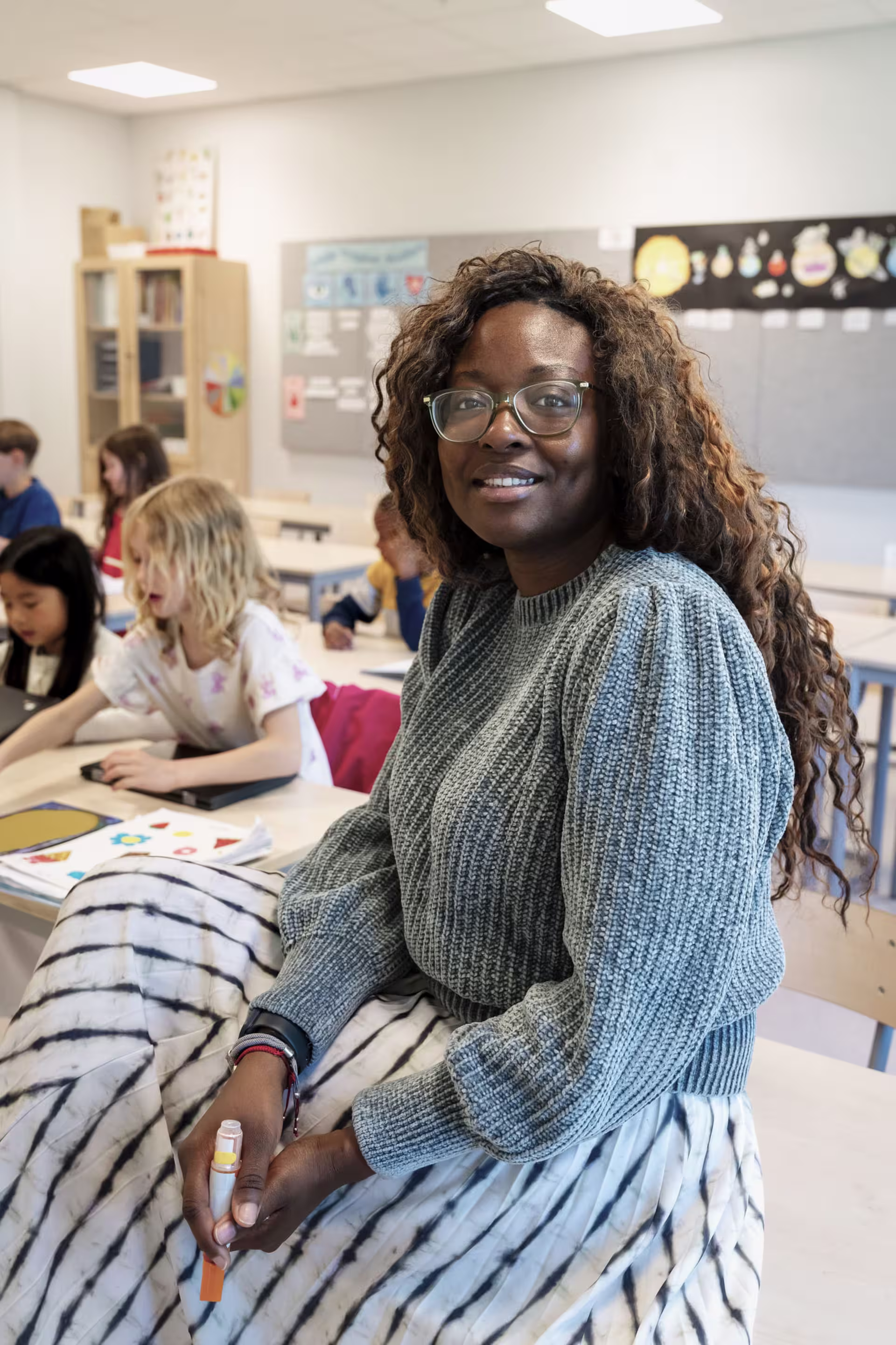Female elementary teacher smiling in classroom.