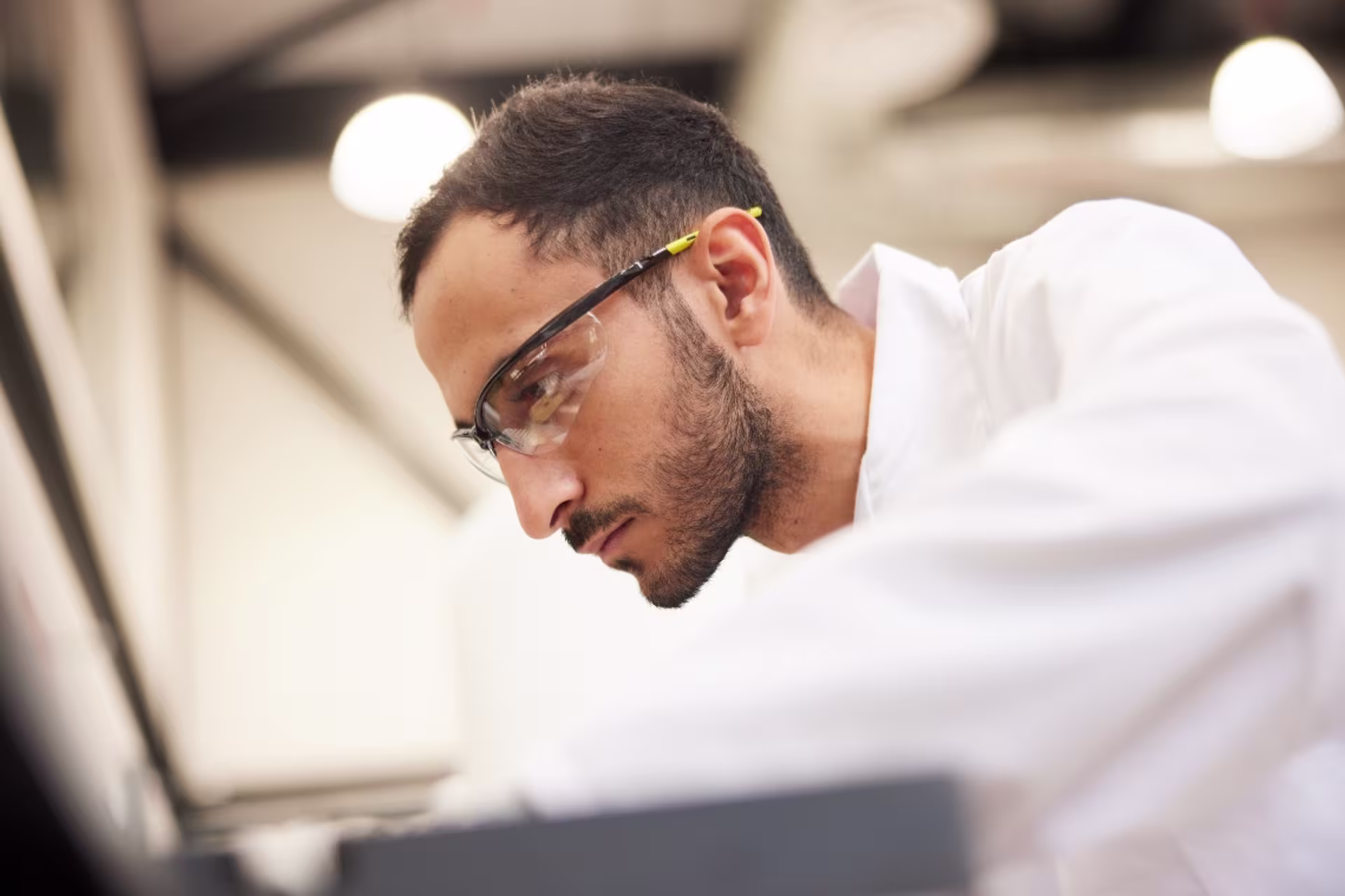 Biomedical engineering student wearing safety goggles and a lab coat and conducting an experiment in a lab setting.