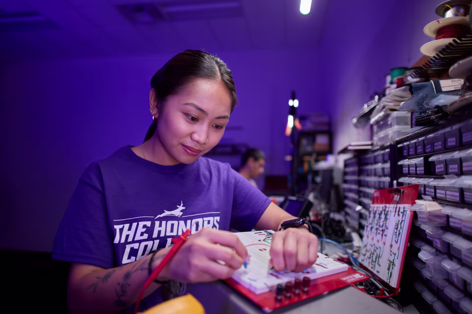 Student working on an electronics project in a lab with organized components and tools.