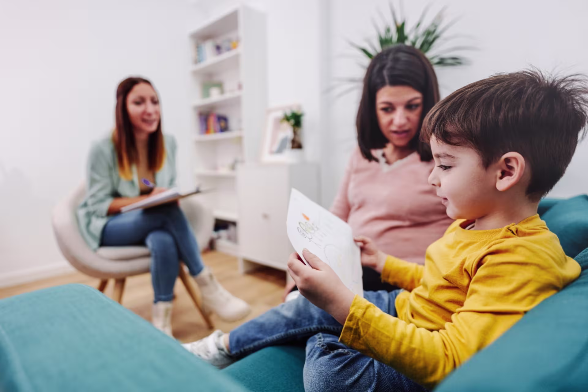 Pregnant mother with her son in a family therapy session with a psychologist in a light, airy office.