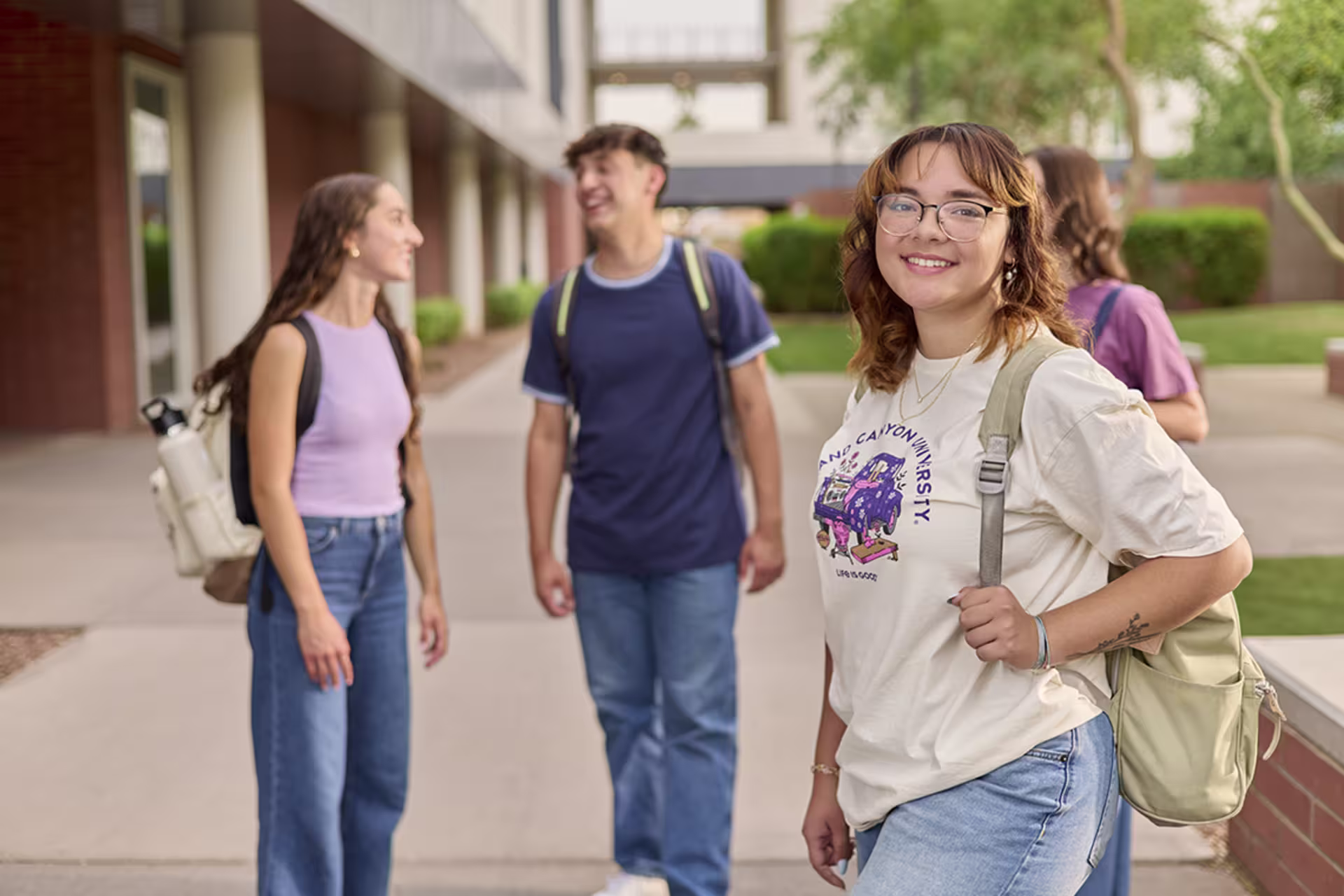 Female undergrad student smiling with fellow classmates behind her outside.